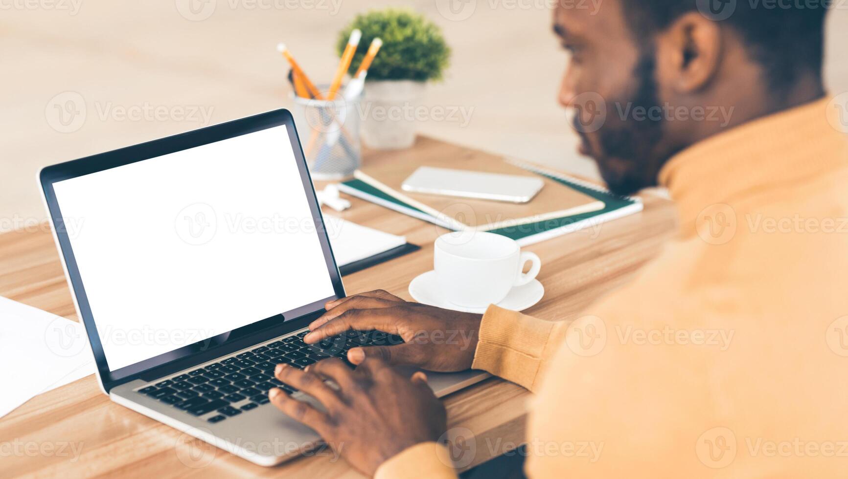 Mock Up Template. Rear view of black man working on laptop with blank screen, typing on keyboard, copyspace photo