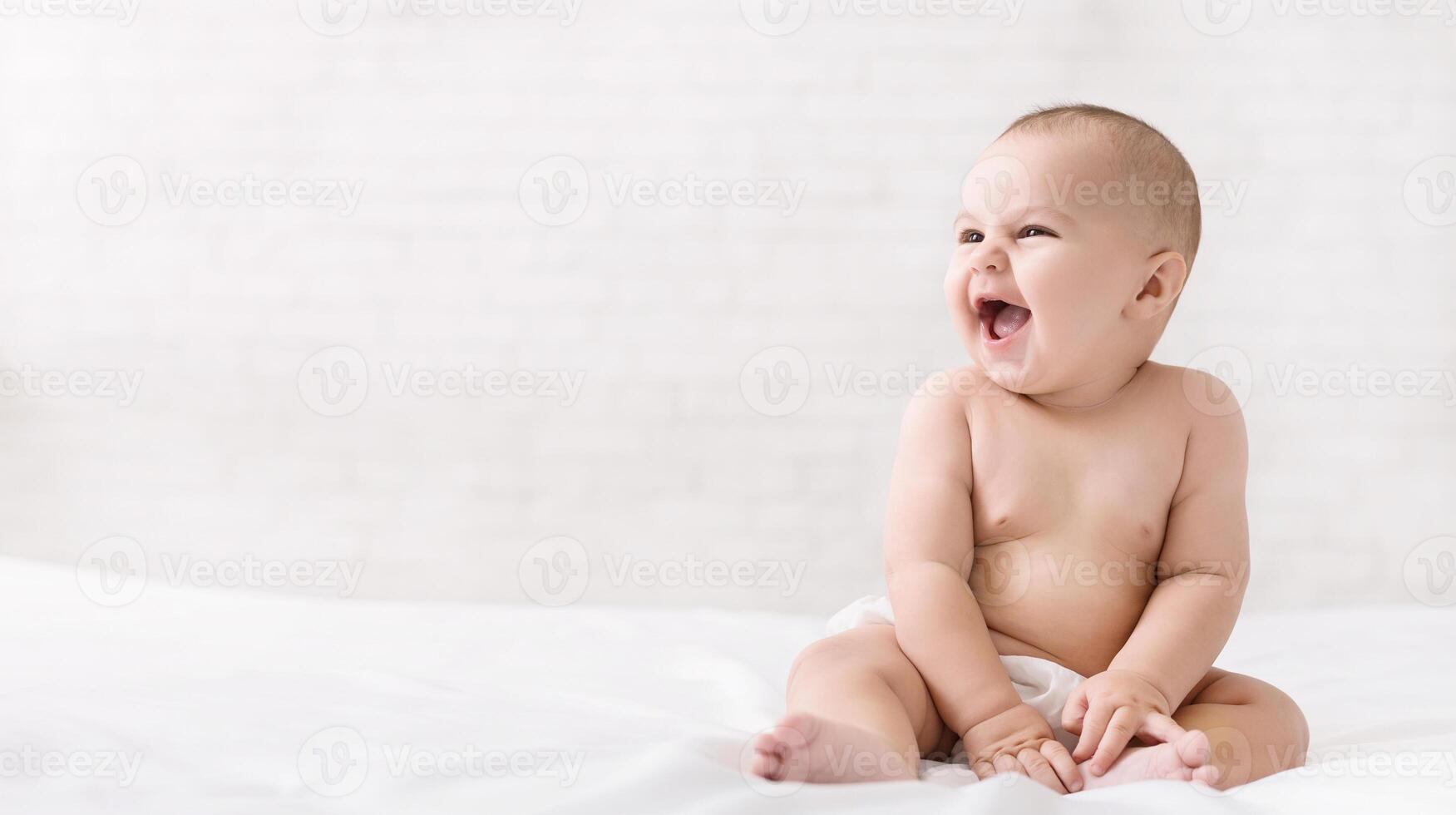 Adorable excited six month baby laughing and looking at copy space on white photo