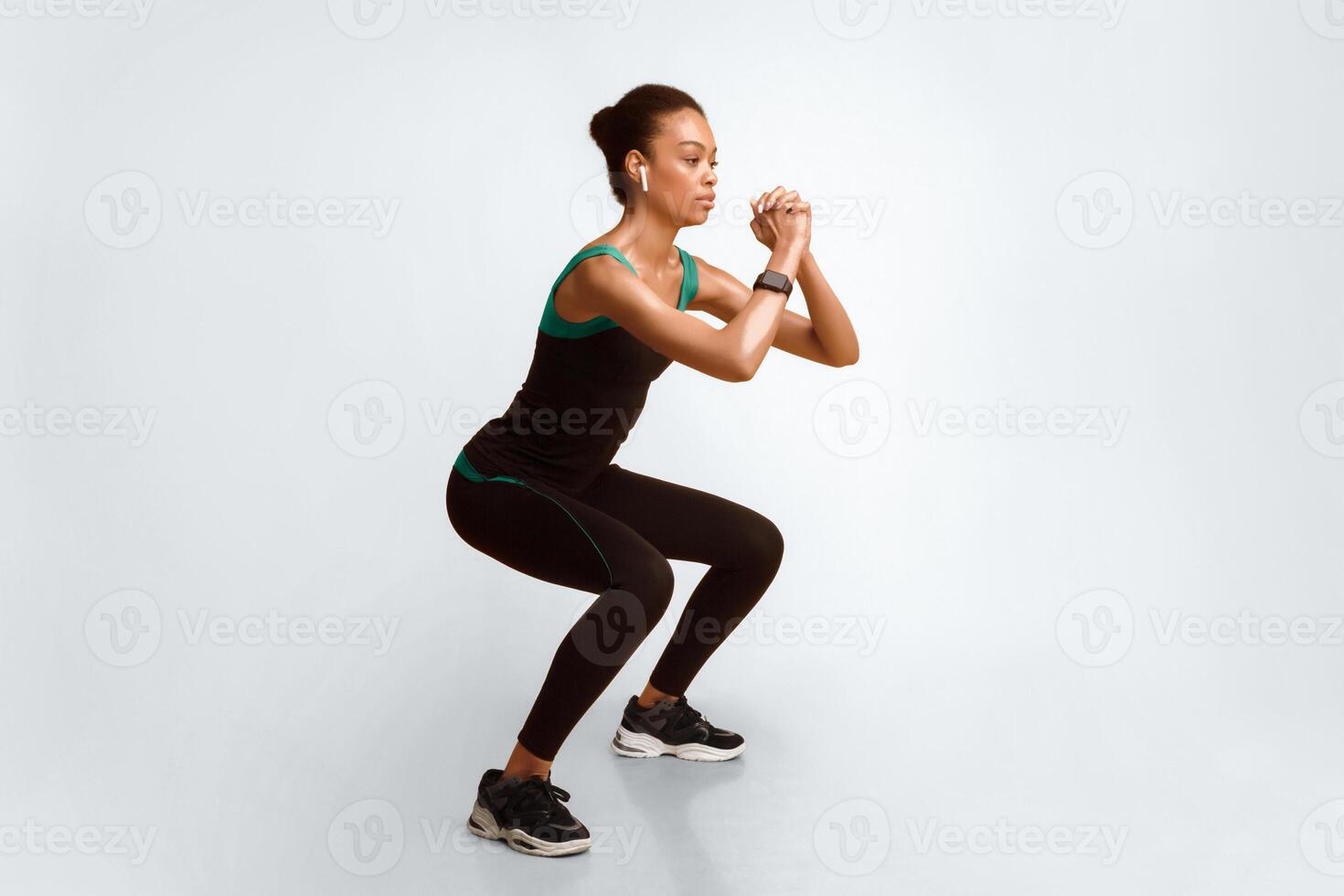 Workout. Black Sporty Girl Doing Deep Squat Exercise On Yellow Background. Studio Shot photo