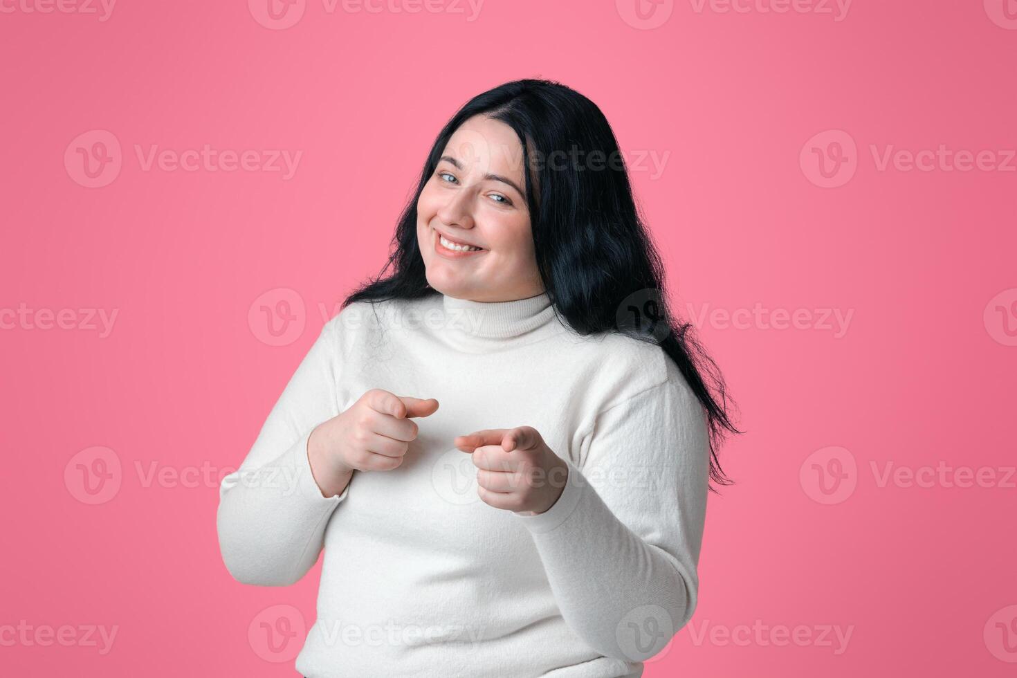 Gotcha. Positive Plus Size Model Pointing Fingers At Camera, Isolated On Pink Background, Free Space photo
