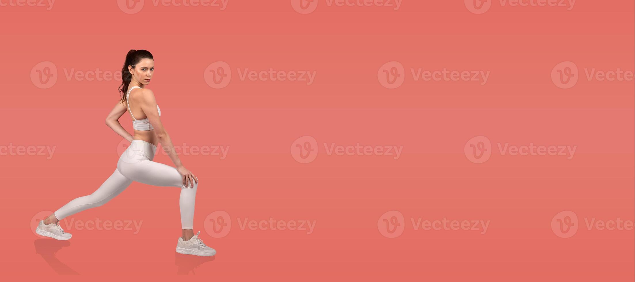 A fitness enthusiast performs a lunging stretch, showcasing proper form and technique. The vibrant background emphasizes the movement, highlighting strength and flexibility. photo