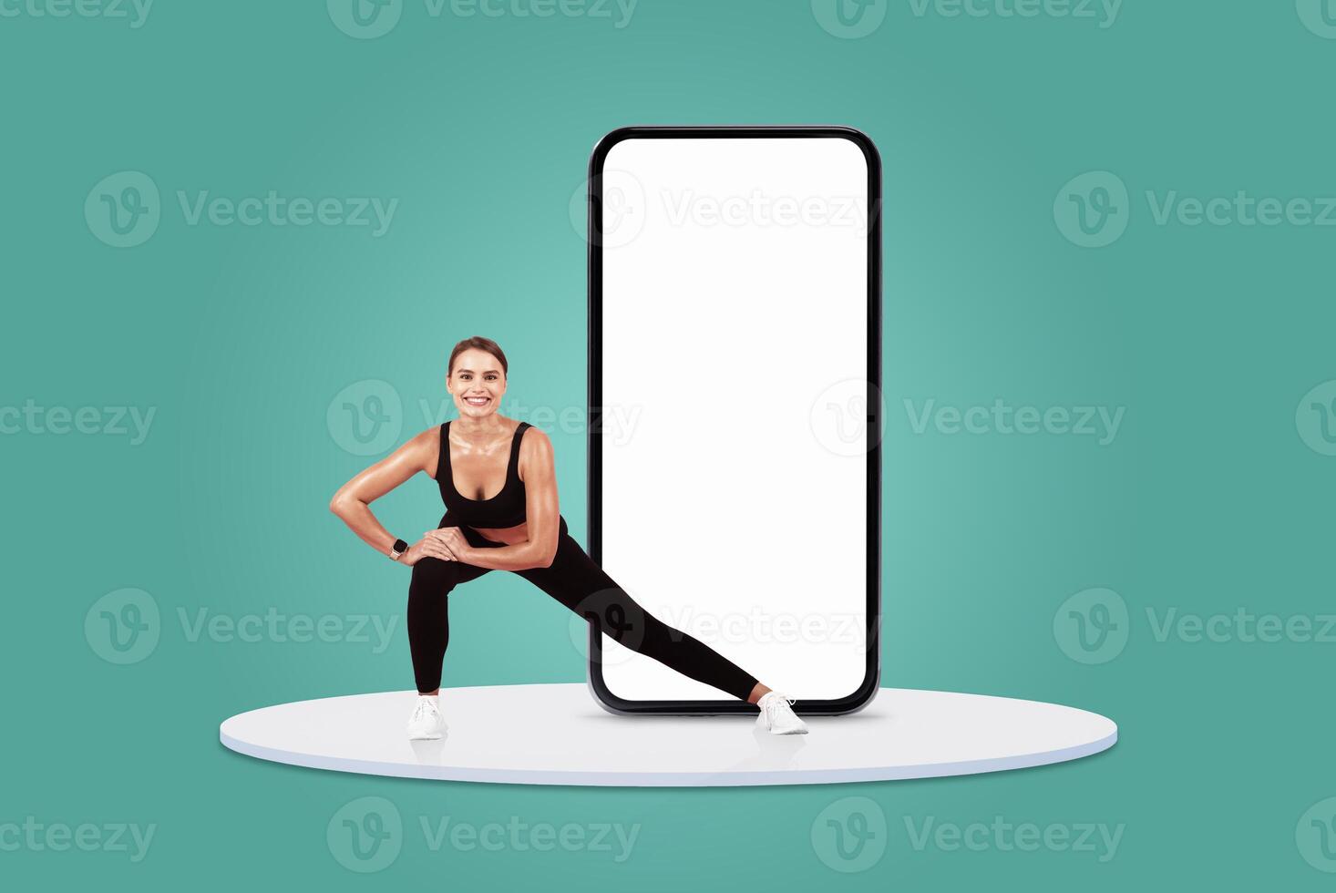 A woman in athletic wear performs a stretching exercise next to a large blank smartphone on a round platform. The background is a vibrant turquoise, adding energy to the setting. photo