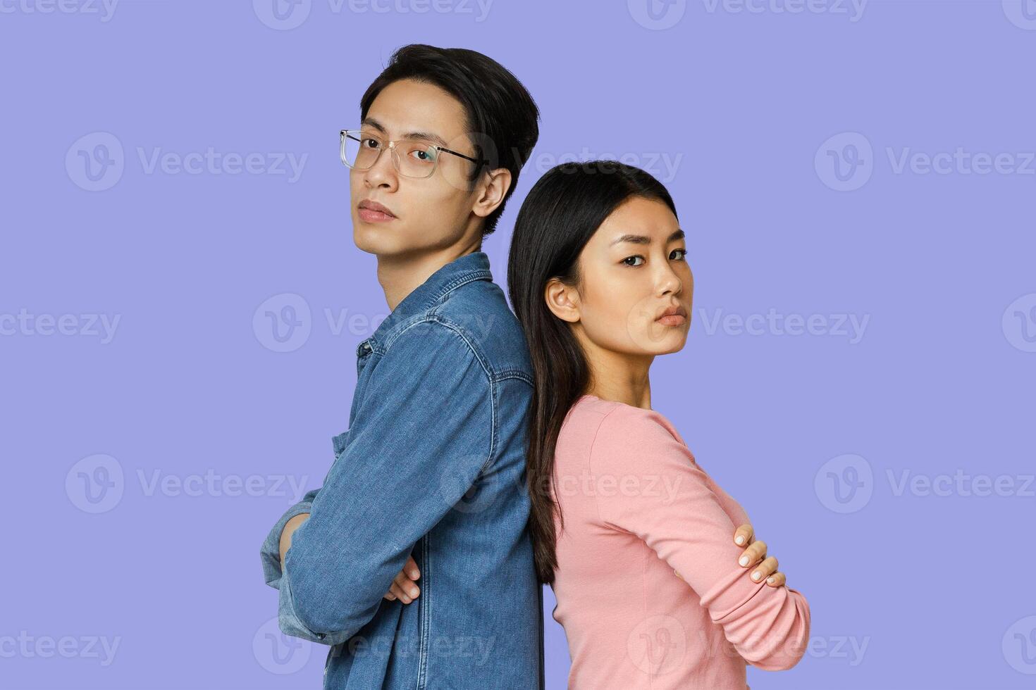Unhappy asian man and woman staying back to back over grey background, misundersatnding in couple photo