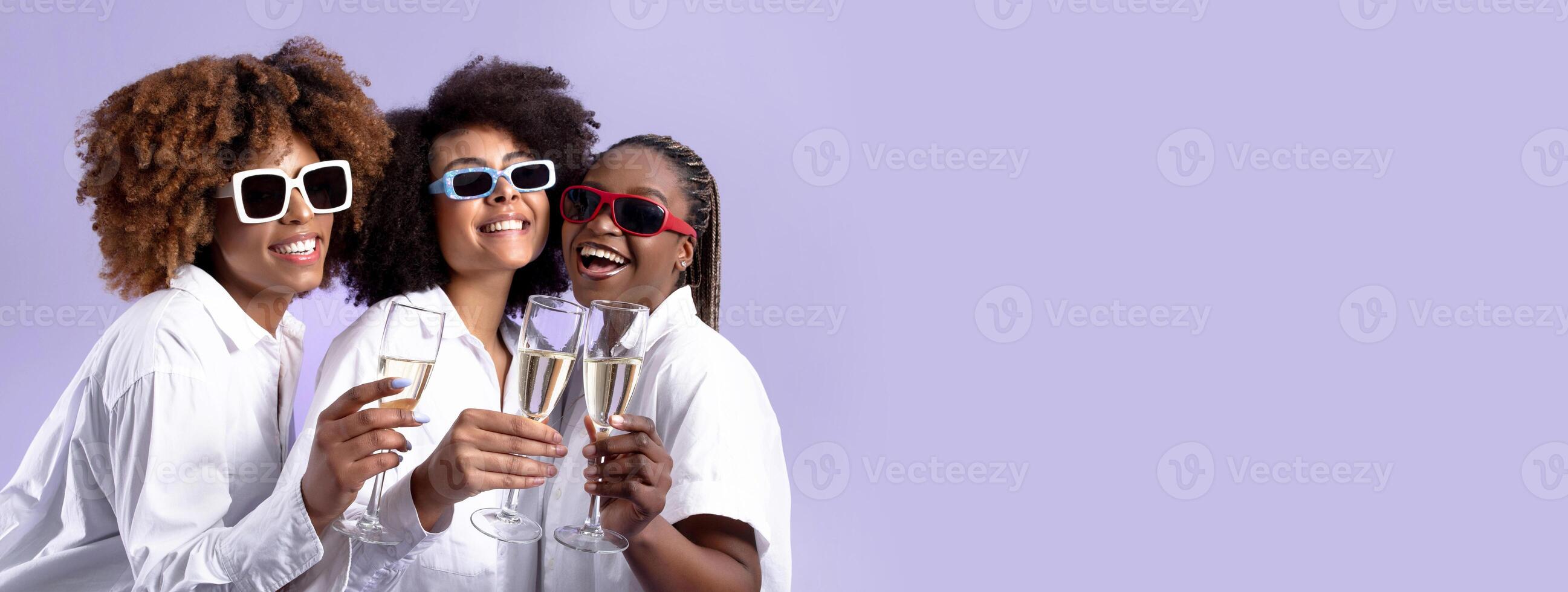 Holiday Celebration Party. Three African American Women Clinking Glasses With Sparkling Wine, Celebrating Special Event Wearing Sunglasses Standing Over Purple Studio Background, Copy Space photo
