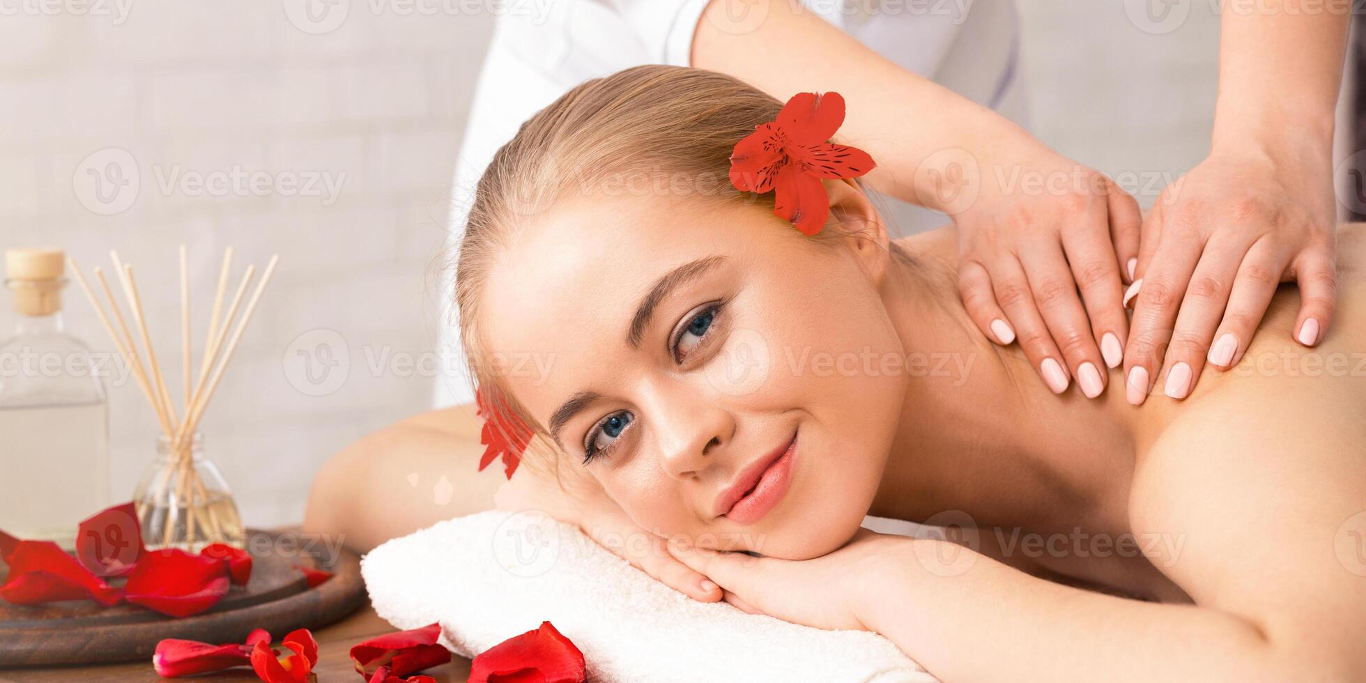 Aroma procedures concept. Smiling girl on table with petals has massage photo