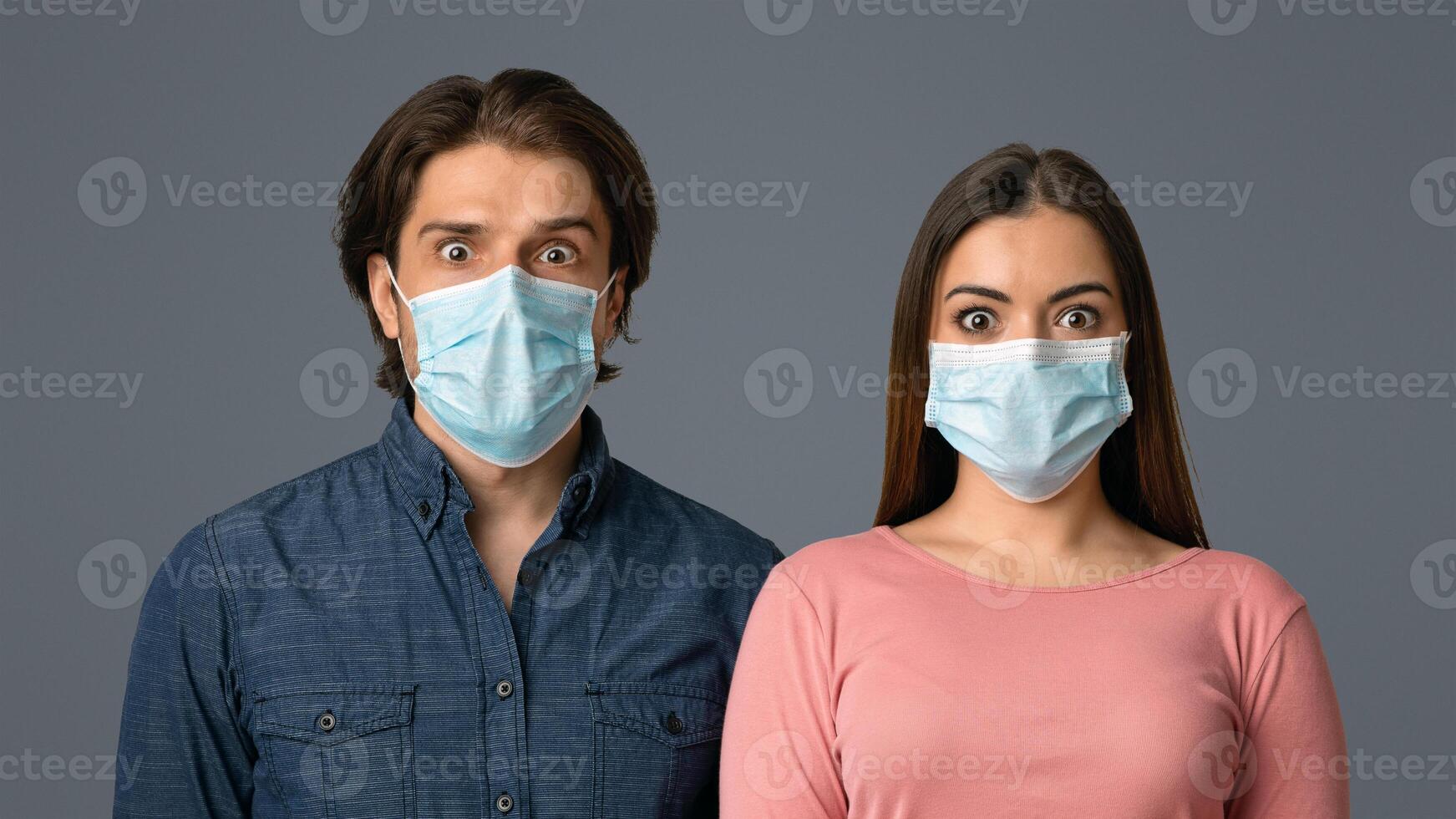 Virus Outbreak Danger. Portrait Of Scared Man And Woman In Protective Face Masks, Looking At Camera With Frightened Face Expression, Light Background photo