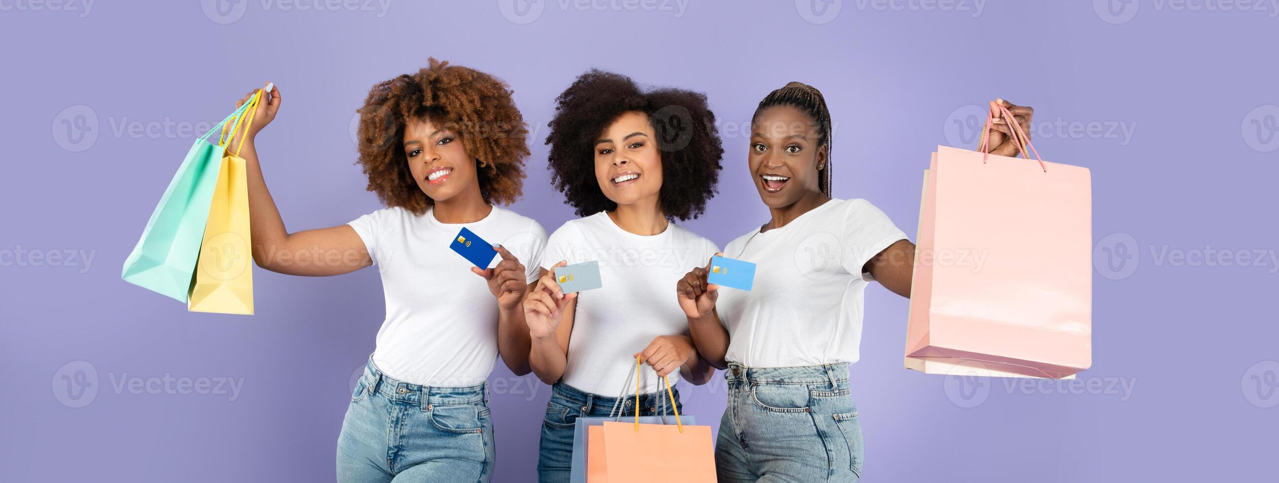 Three black friends are celebrating their shopping excitement, showcasing colorful shopping bags and cards against a solid purple background, highlighting a joyful retail experience together. photo
