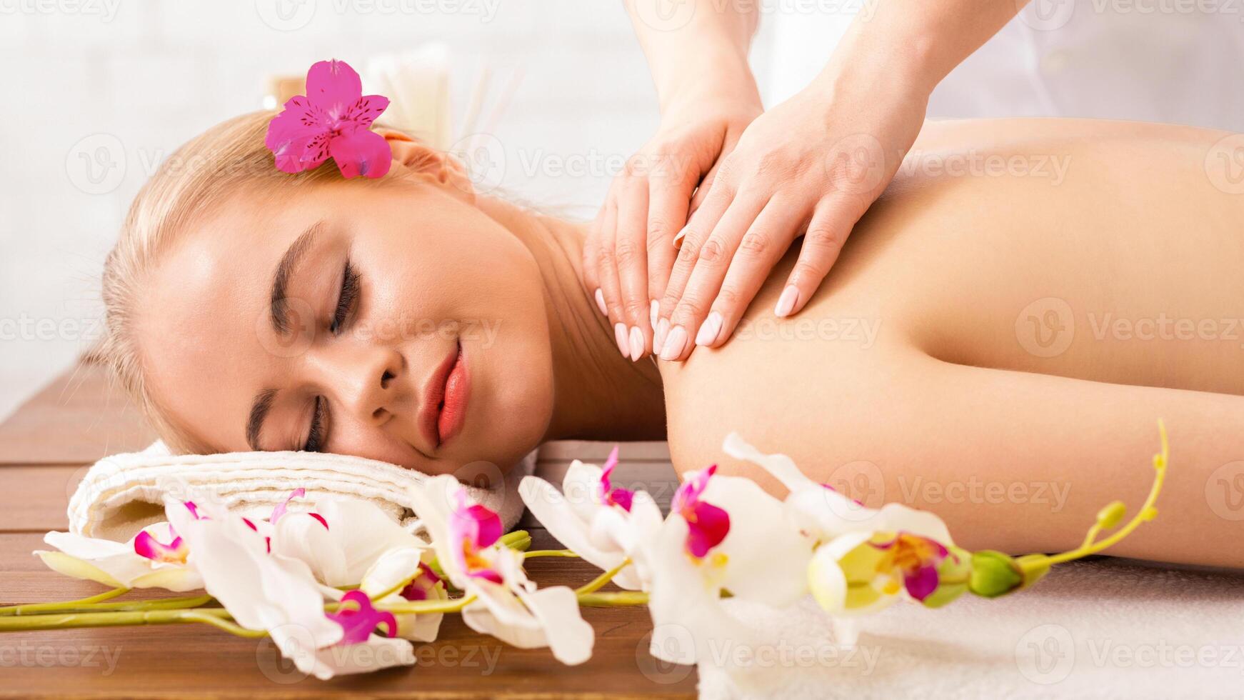 Spa woman massage. Portrait of girl on table with orchids photo