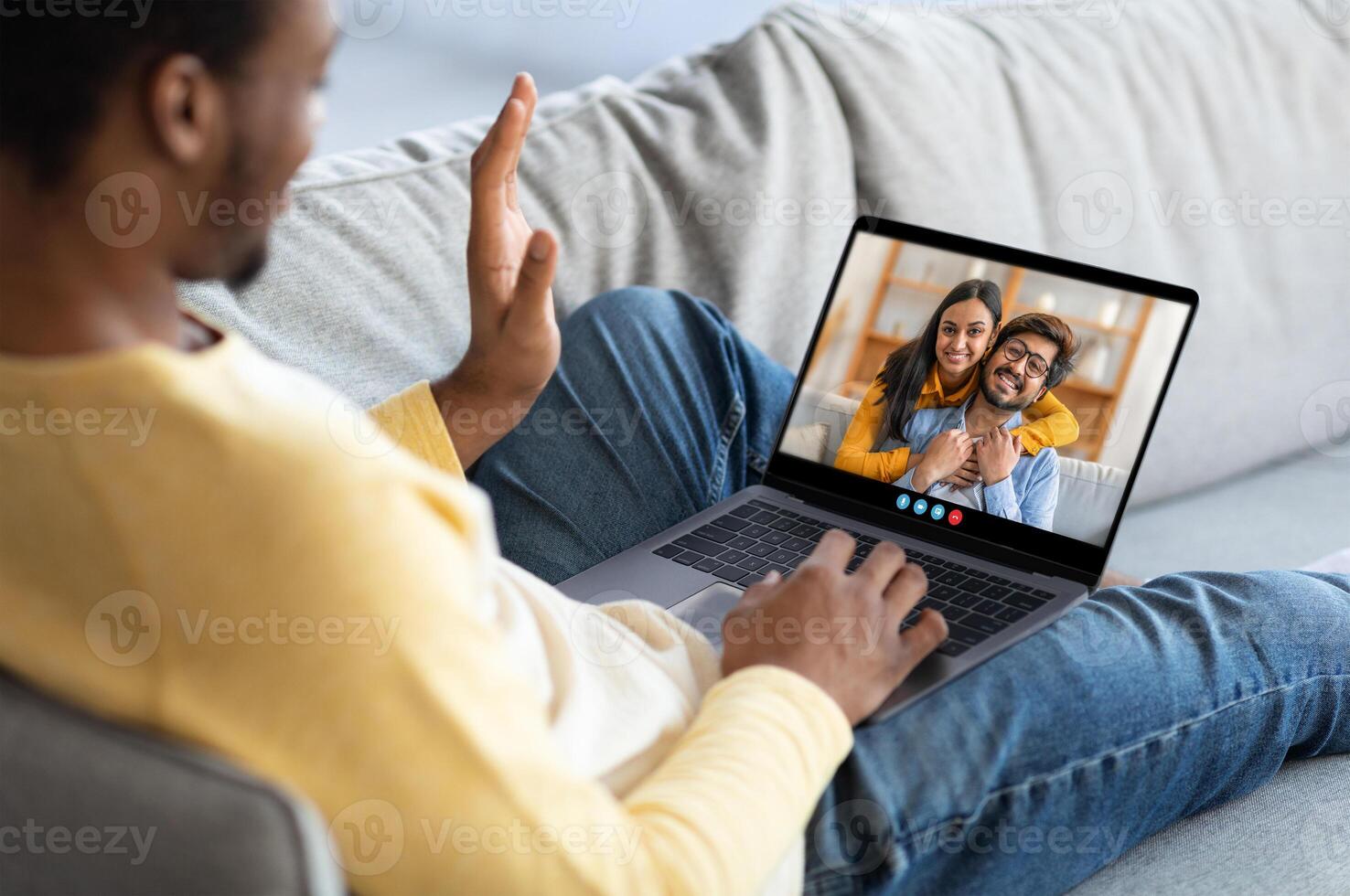 Two friends share a heartfelt moment during a call on a laptop while sitting on a comfy couch, conveying warmth and connection in a relaxed indoor setting. photo
