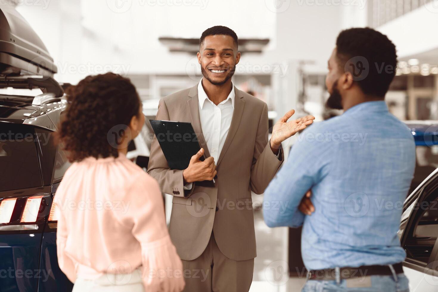 Car Selling Business. Salesman Consulting Customers Showing Automobiles In Auto Store. Selective Focus photo