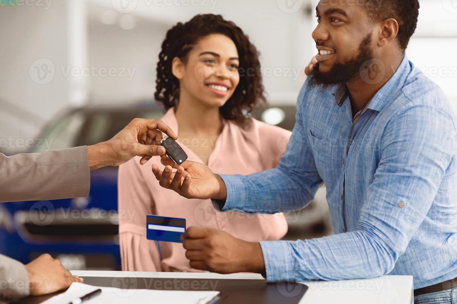Buying Auto. Afro Spouses Paying With Credit Card Purchasing New Car In Dealership Office. Cropped, Selective Focus photo