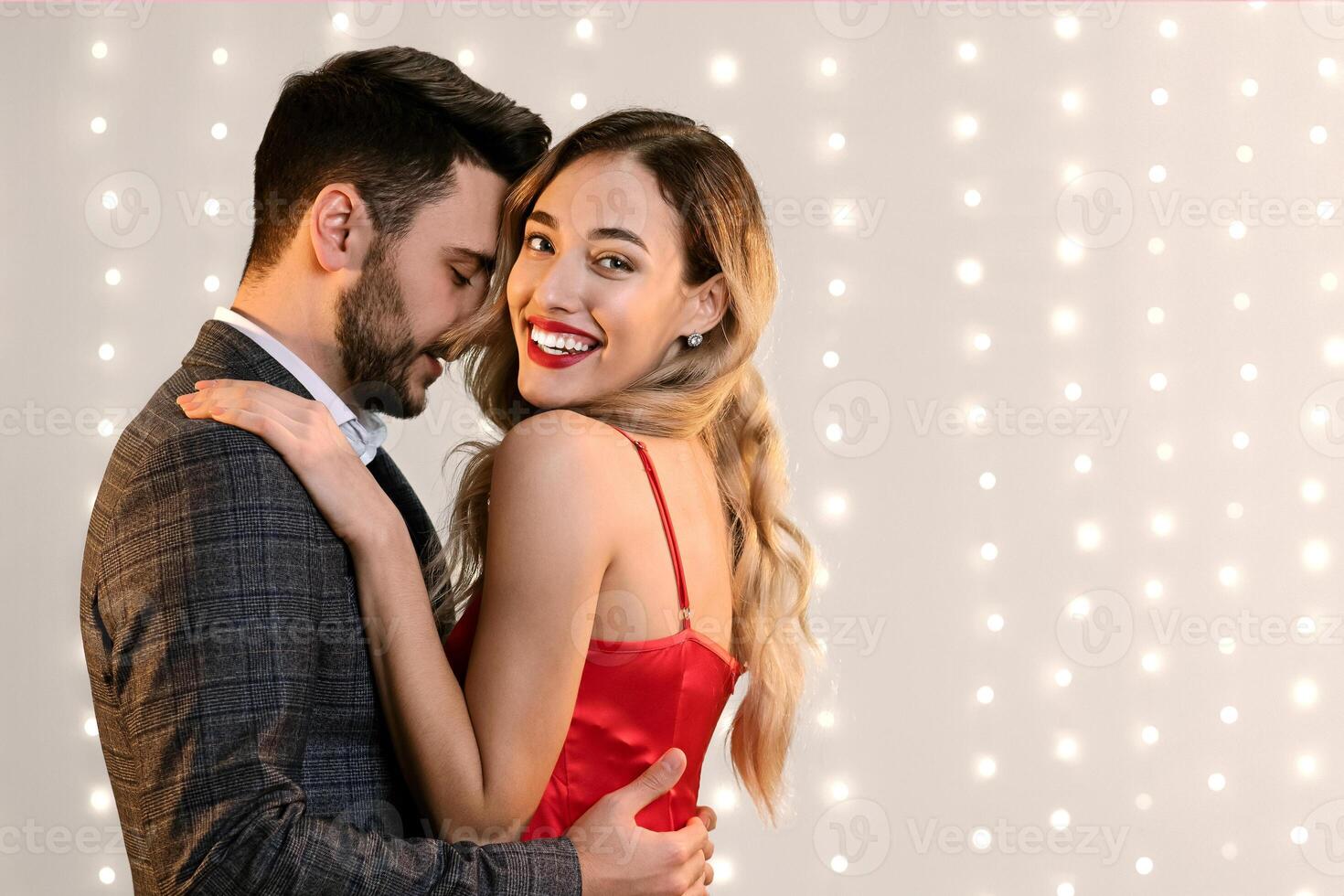 Attractive young couple embracing and bonding while standing over beige background indoors, free space photo