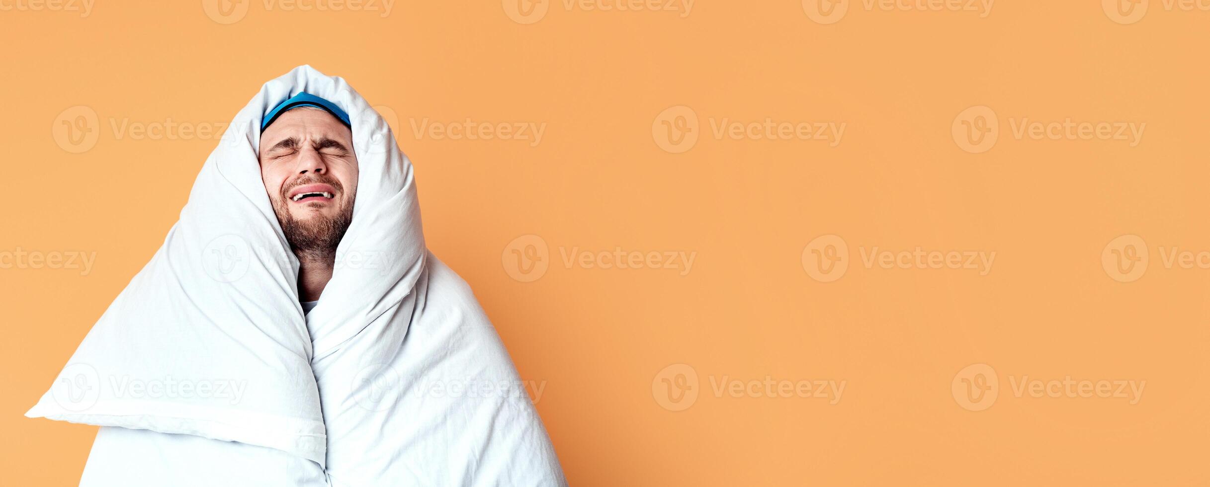 Doesnt want get up. Funny sad man wrapped in blanket on yellow background photo