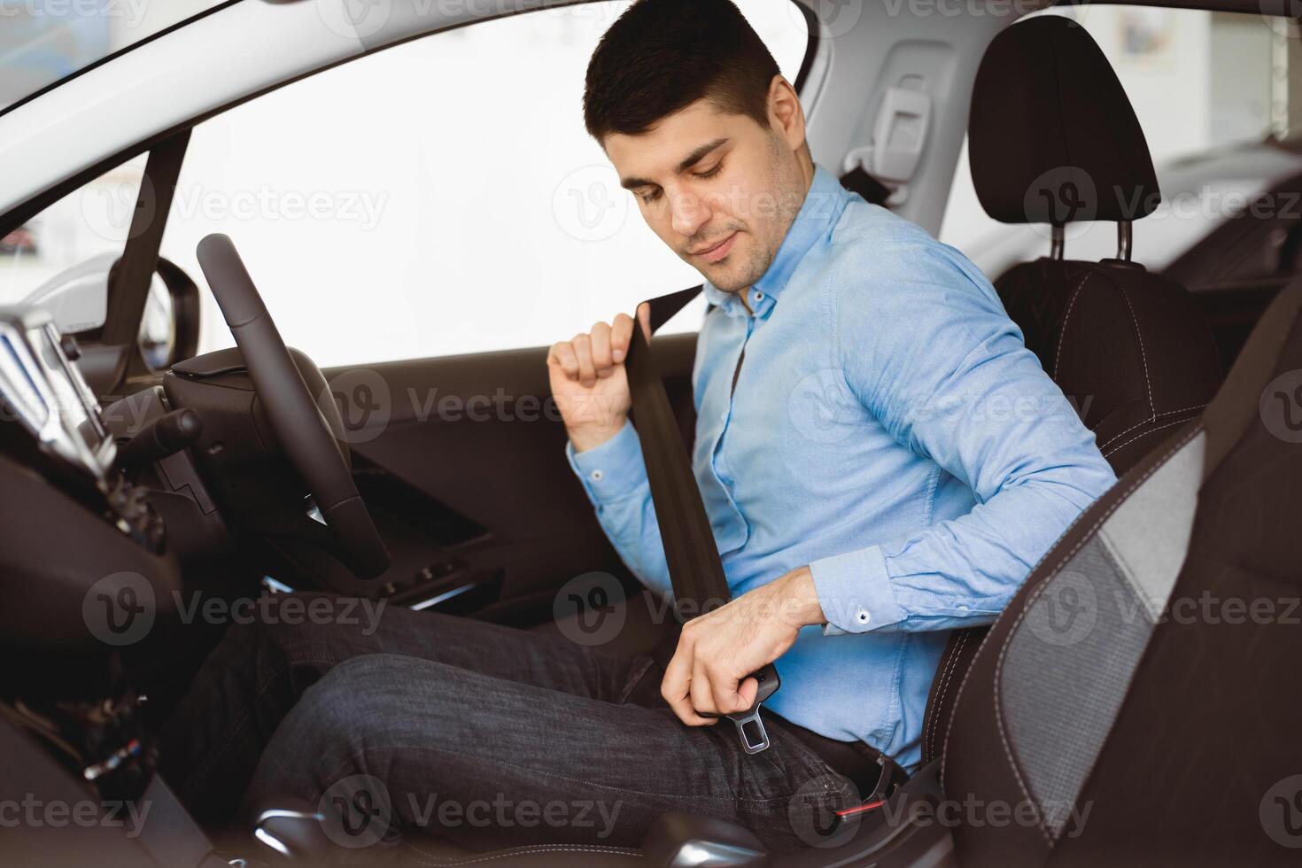 Car Safety. Young business man fastening seat belt in auto, driving to work photo