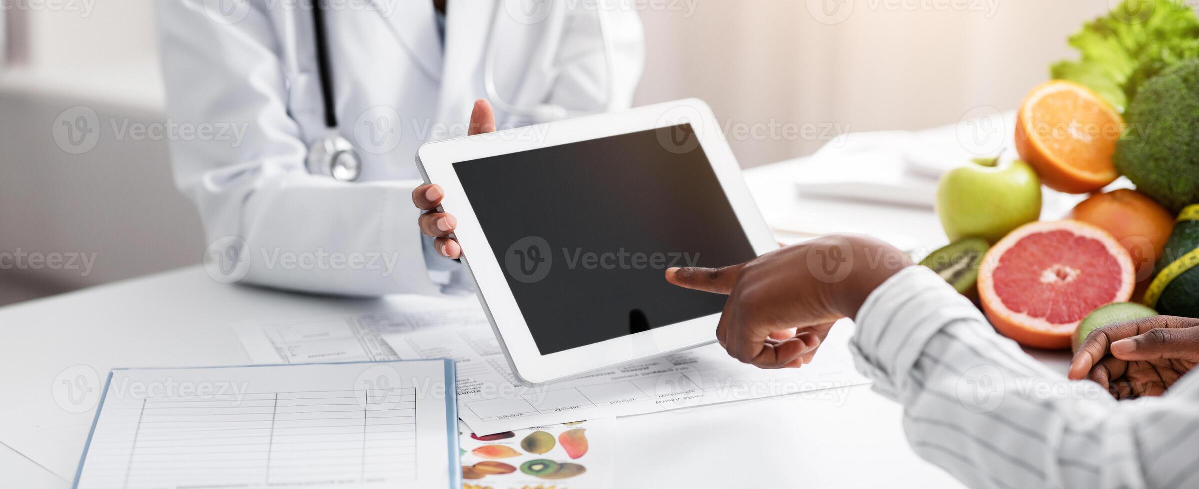 African woman patient of dietician touching empty digital tablet screen, cropped, application for healthy diet photo