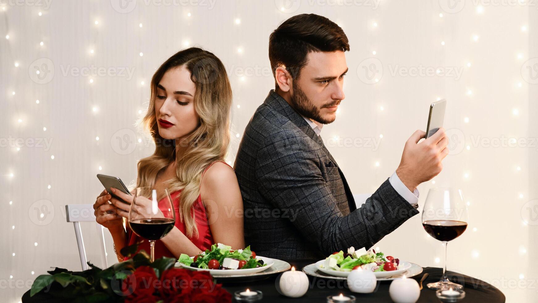 Date Fail. Bored Couple Using Smartphones Sitting Back To Back On Romantic Dinner In Restaurant, Ignoring Each Other. photo