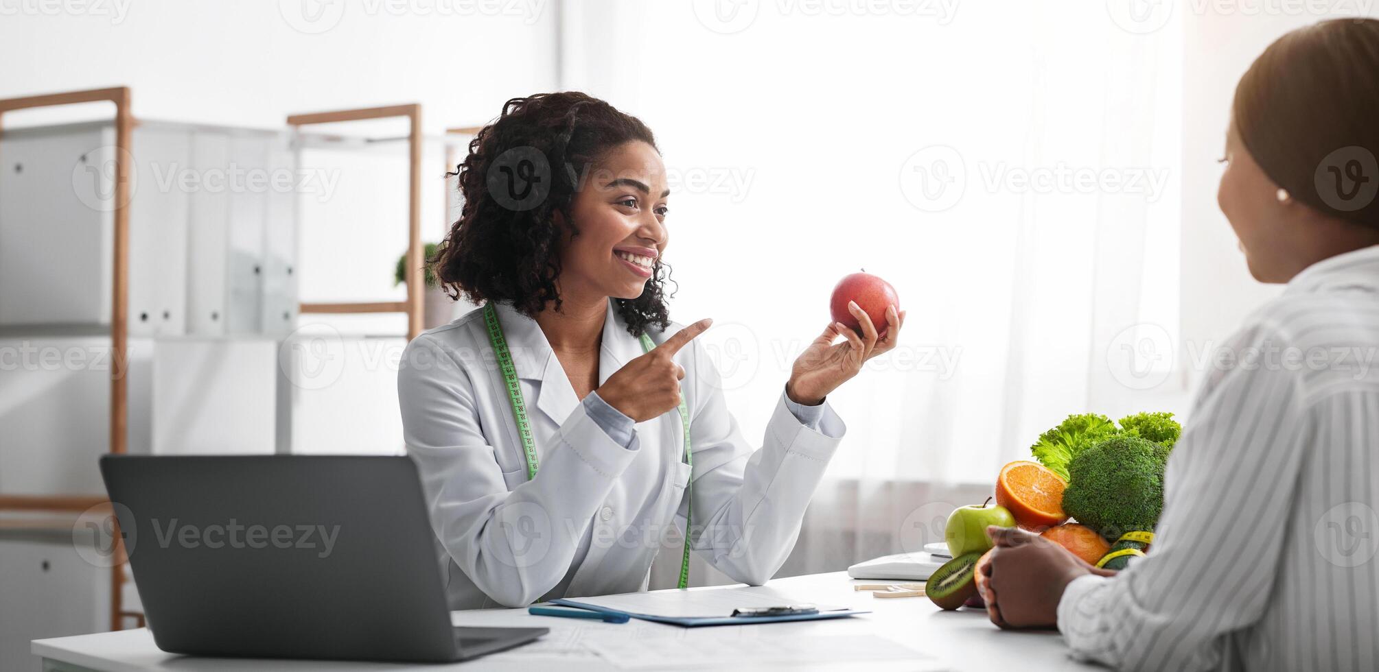 Pretty nutritionist black woman giving consultation to patient with healthy fruit and vegetable, nutrition and diet concept, copy space photo