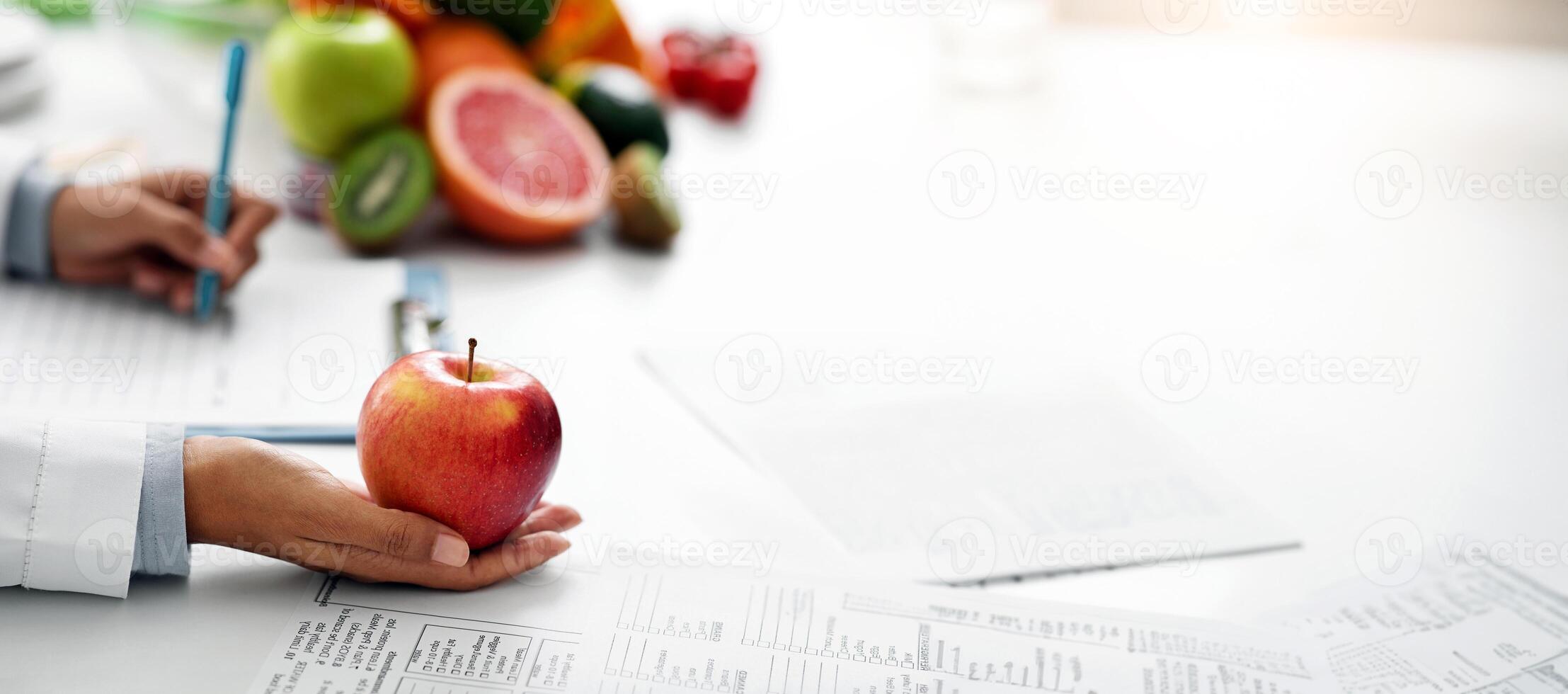 Close up of female afro doctor holding big fresh red apple, black lady having session with dietologist photo