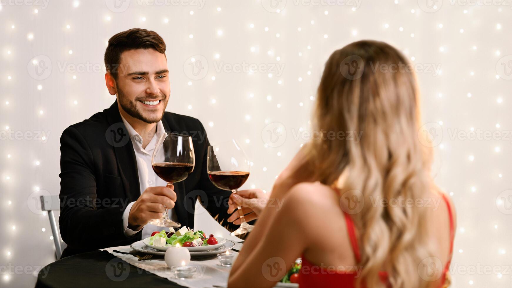 Toast For Us. Romantic couple clinking red wine glasses during Valentine Day dinner in restaurant. selective focus to man photo