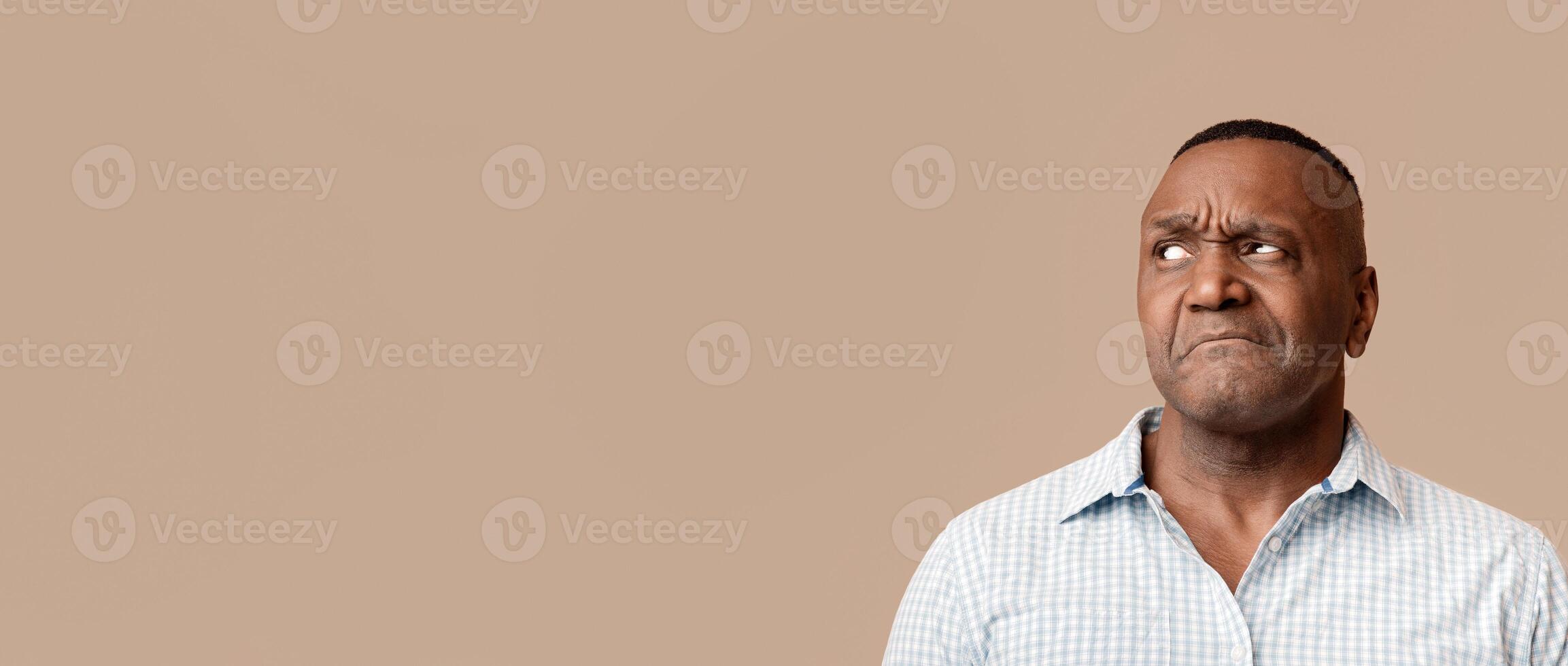 Skeptical mature african man looking aside at free space on orange background. On his own mind photo