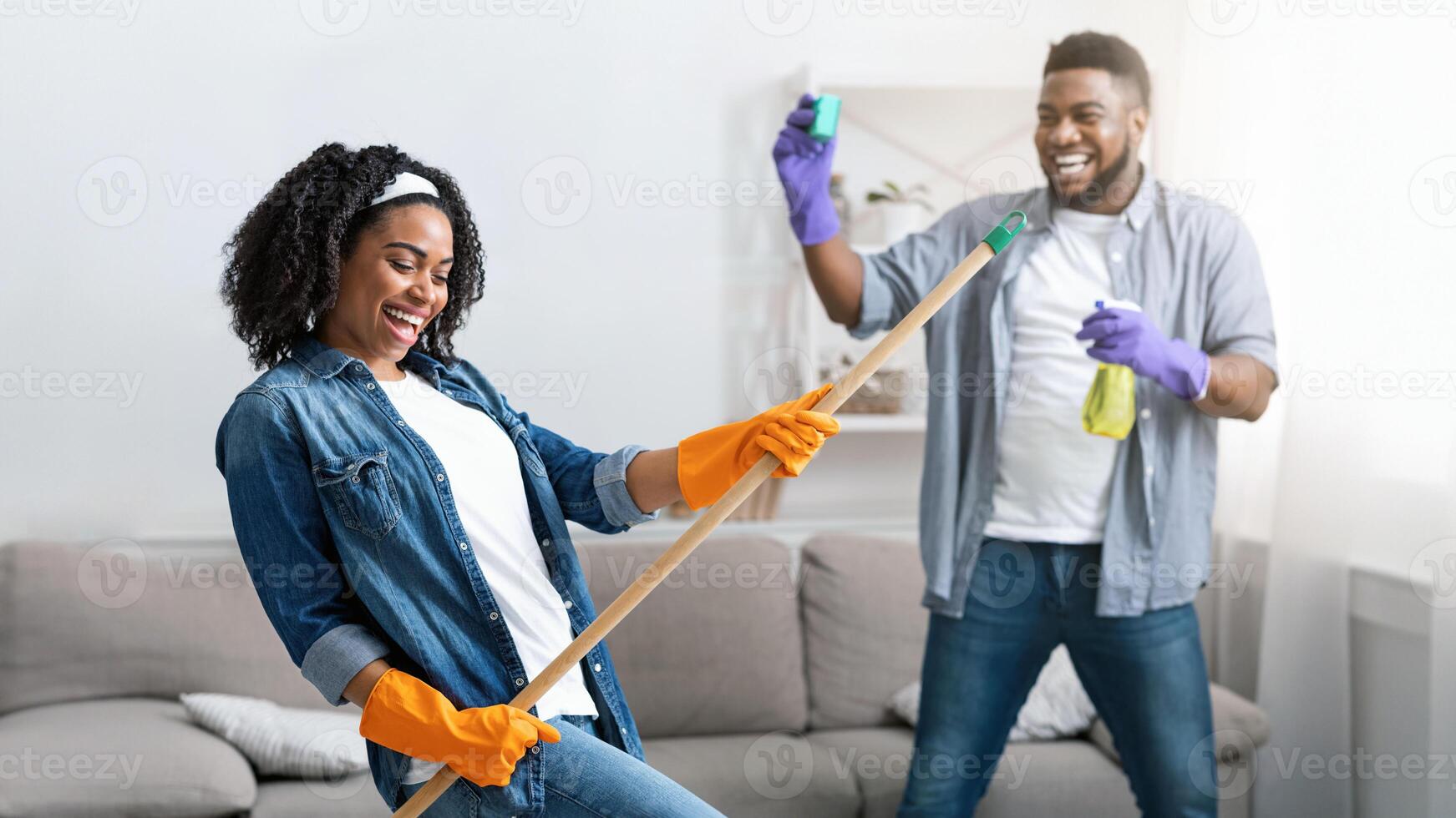 Spring-Cleaning With Fun. Joyful African American Couple Fooling Together While Tidying Their Apartment, Selective Focus On Woman photo