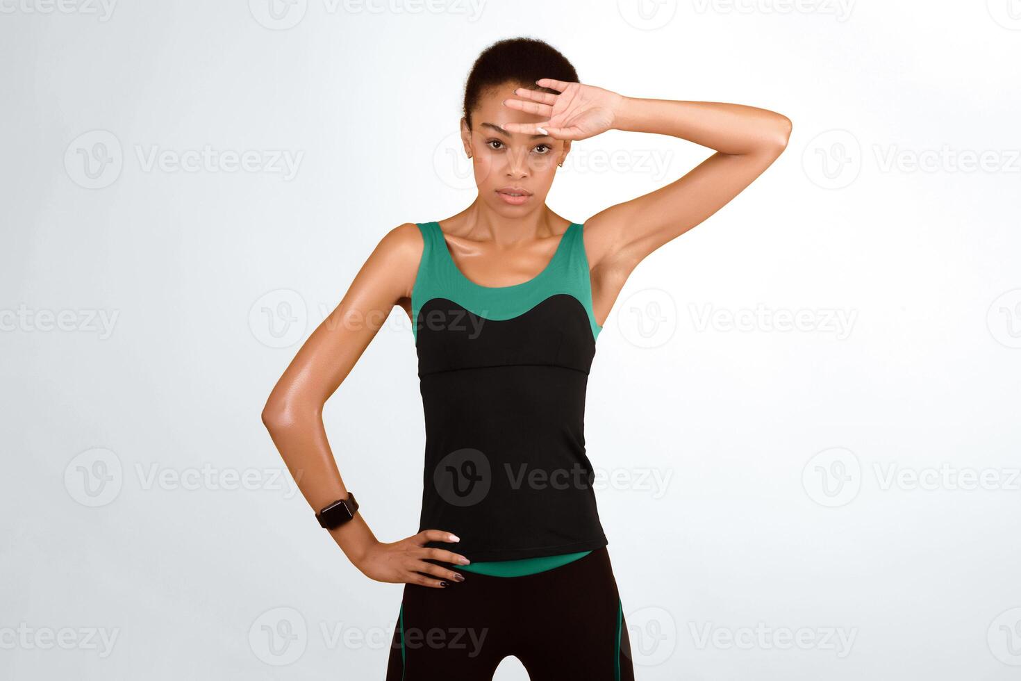 Fitness Concept. Sporty Afro Girl Wiping Sweat From Face After Workout Training Standing Over Yellow Studio Background photo
