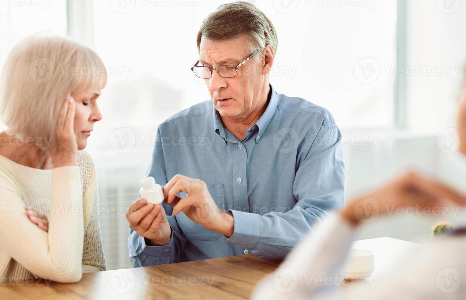 Medical Prescription. Senior man with his wife looking at pills at doctor's office, copyspace photo