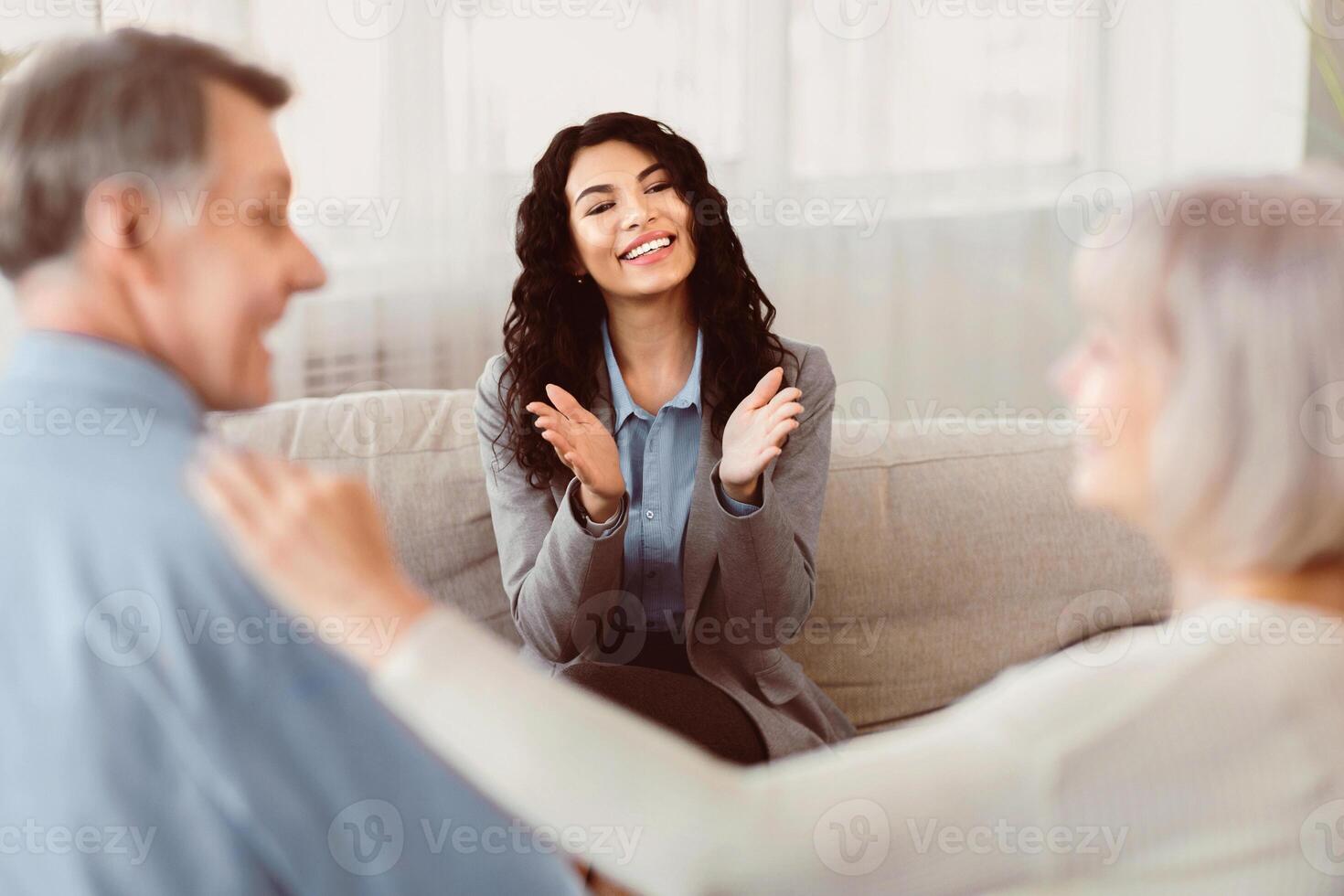 Appreciating Success. Happy latin psychologist clapping hands at meeting, back view of loving senior couple photo