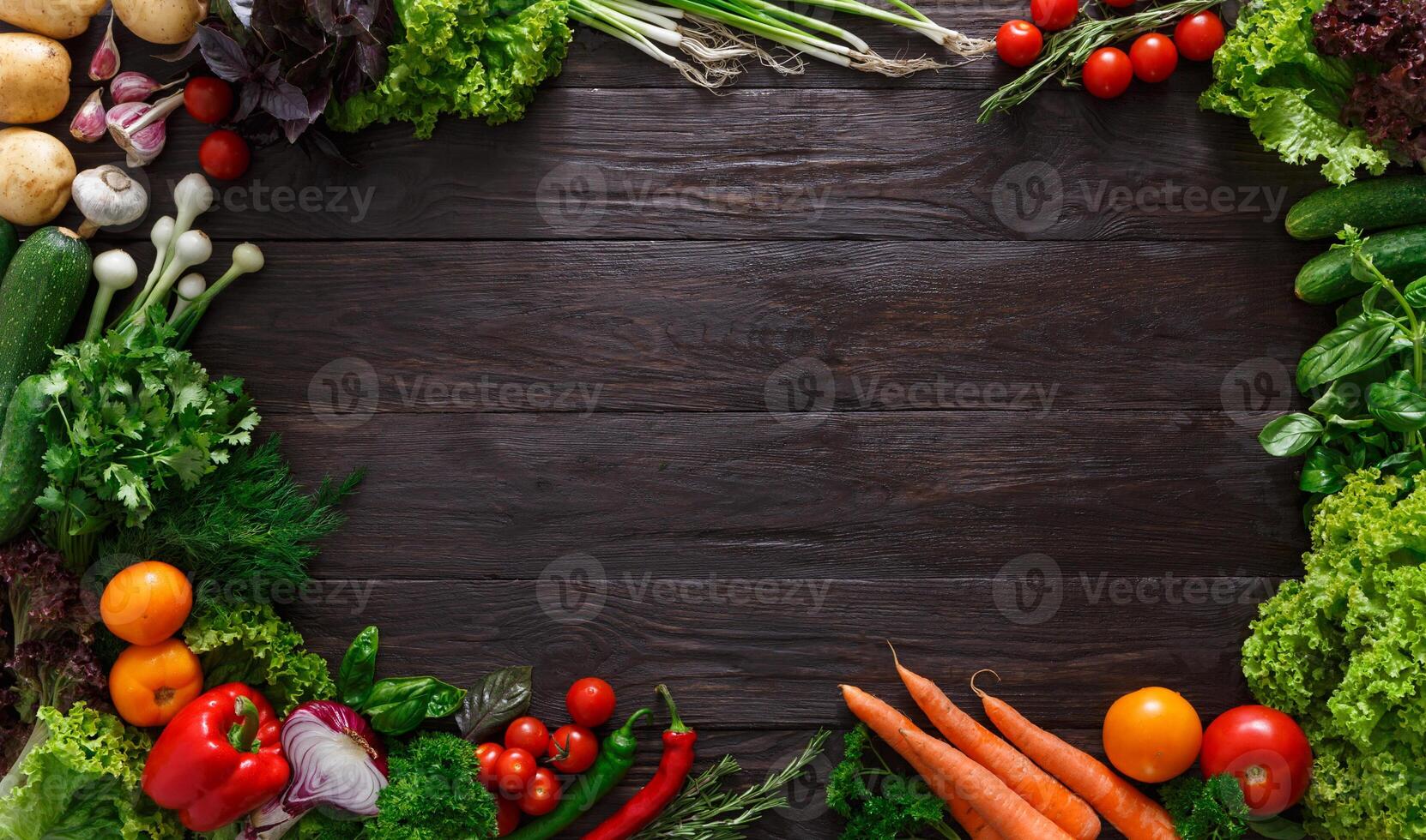 Frame of fresh organic vegetables on wood background. Healthy natural food on rustic wooden table with copy space. Tomato, lettuce, carrot, garlic, pepper and other cooking ingredients top view photo