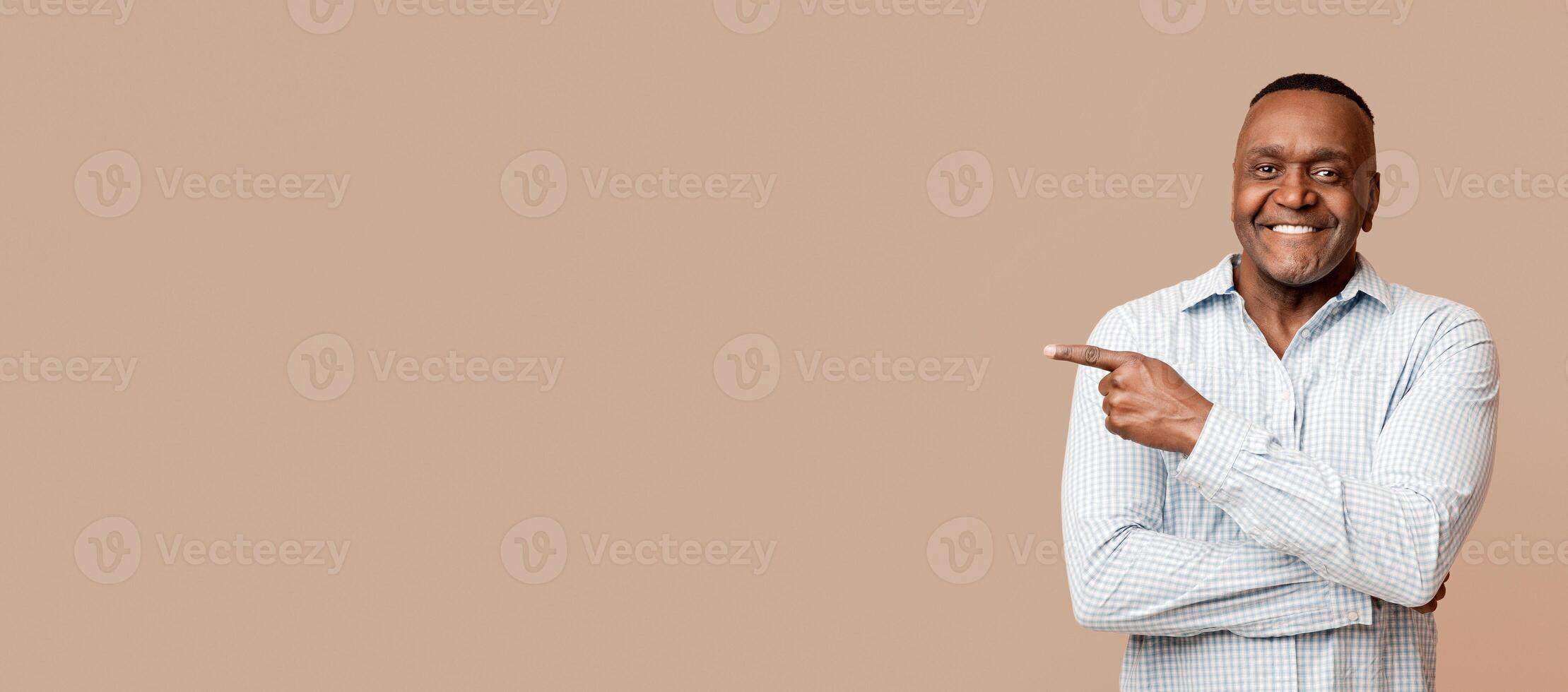Choose this. African american mature man pointing aside at empty space, orange panorama background photo