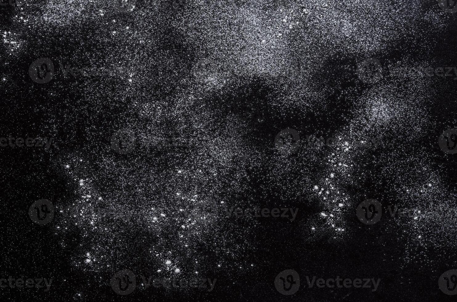 Abstract background. Wheat flour spots on black. Top view on blackboard. Baking concept, cooking dough or pastry. photo