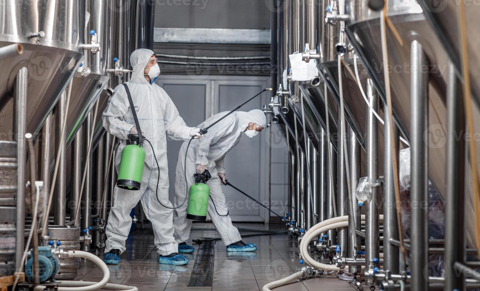 Craft brewery, eco product and disinfection. Workers in hazmat suits clean plant and kettles during quarantine, side view, free space photo