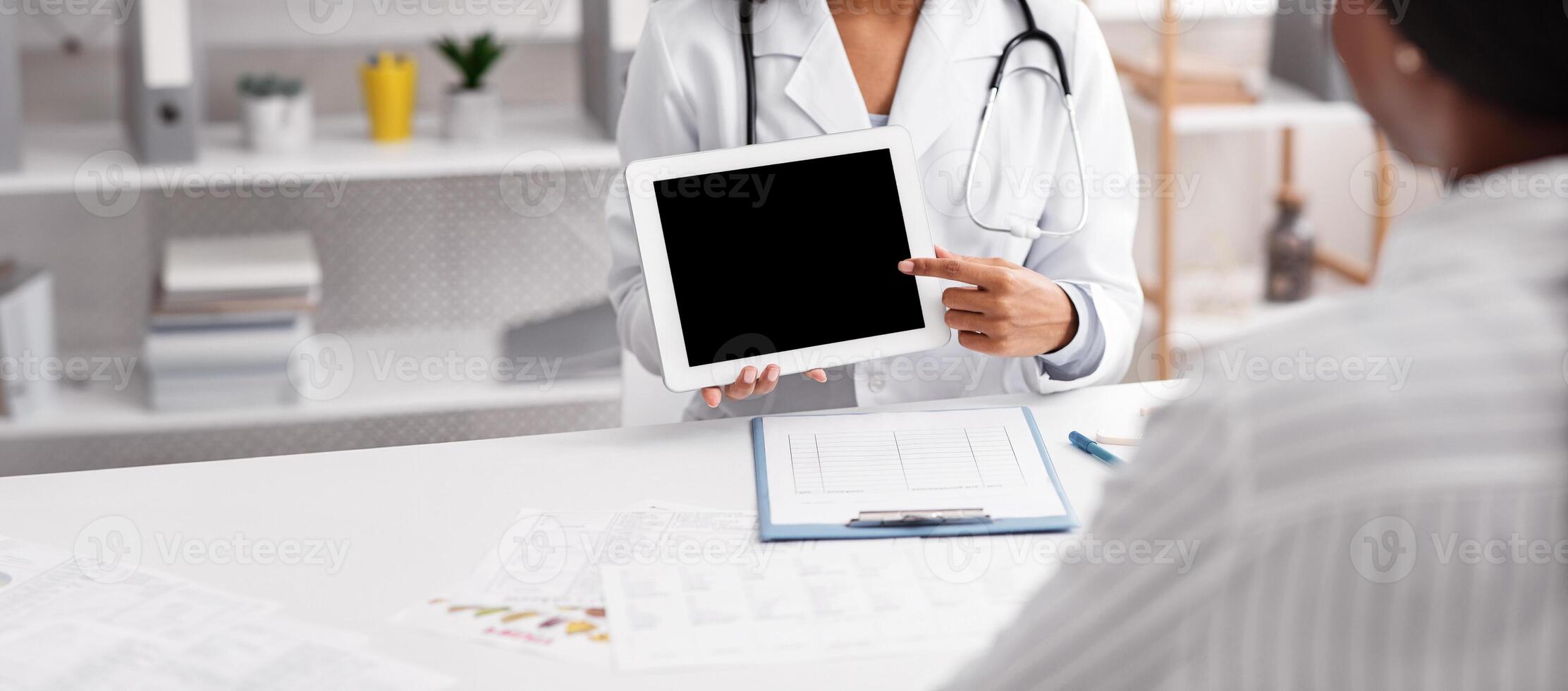 Young black lady doctor consultating patient, showing empty digital tablet with blank screen, cropped photo