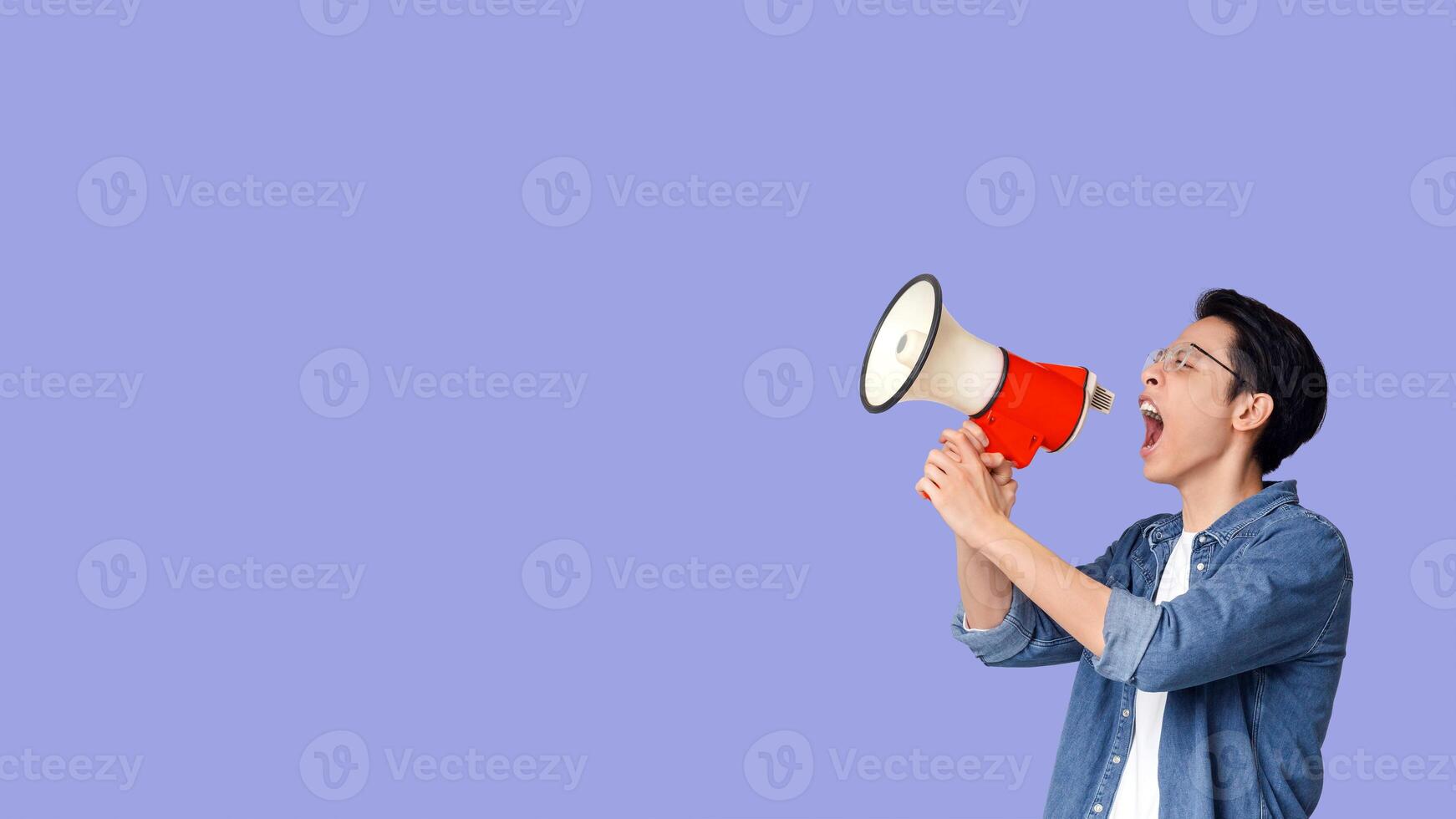 Attention. Emotional asian young man using loudspeaker over grey studio background, panorama with copy space photo