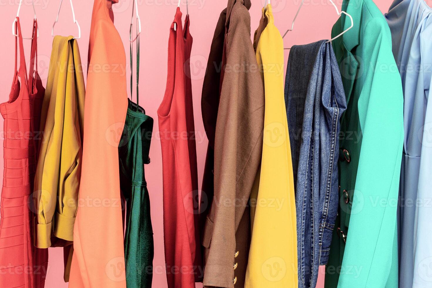 Shopping. Conceptual Shot Of Clothing Rail With Trendy Clothes Over Pink Background In Studio. Colorful Outfits Hanging On Hangers. Fashion And Style, Stylish Wardrobe Concept photo