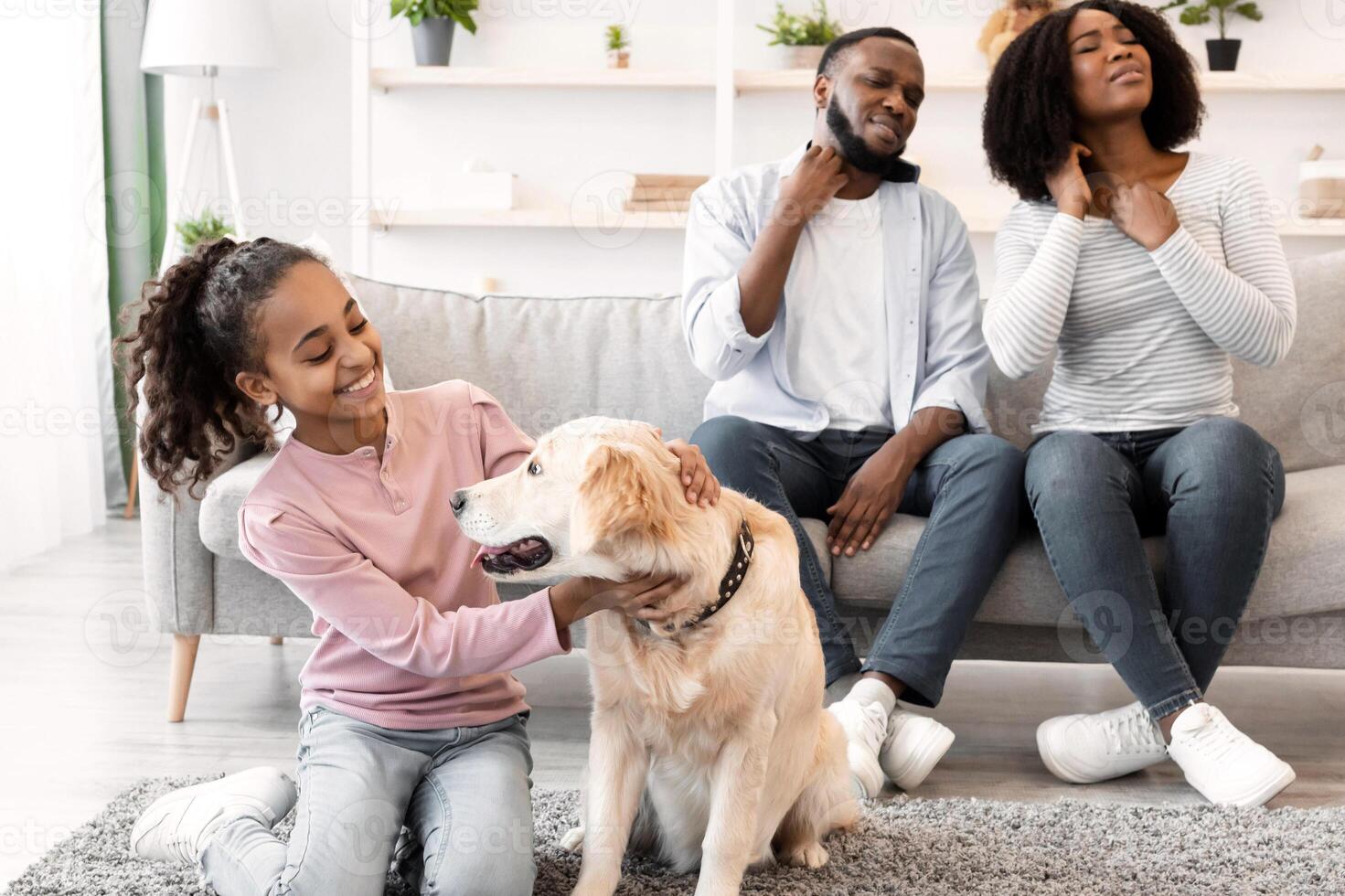 Skin Reactions To Pet Allergy. African American man and woman scratching their itchy necks, suffering from dermatitis caused by their dog, sitting on sofa in blurred background, girl playing with lab photo