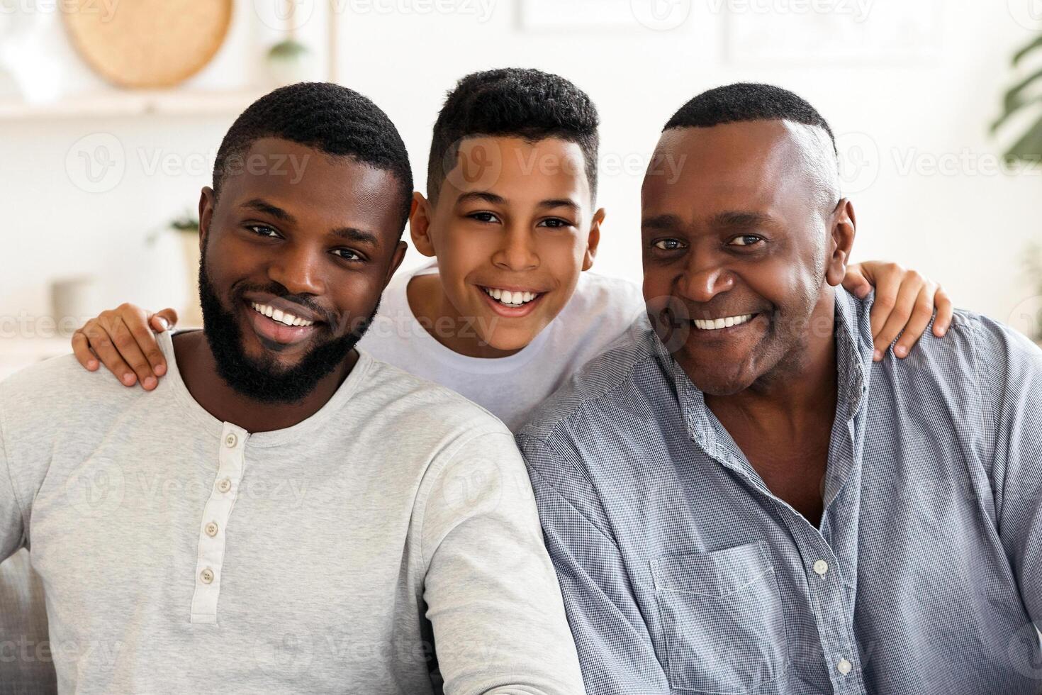 Generation. Smiling Black Boy Embracing His Dad And Grandfather Posing To Camera At Home, Sitting Together On Couch In Living Room. photo