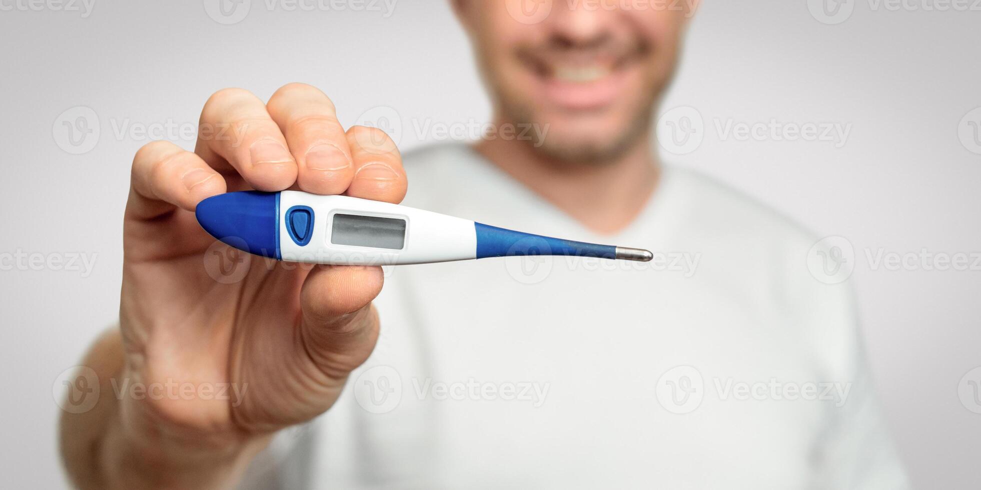 Illness Recovery. Healthy Man Showing Thermometer With Normal Temperature Smiling To Camera Over Gray Background. Panorama, Selective Focus photo