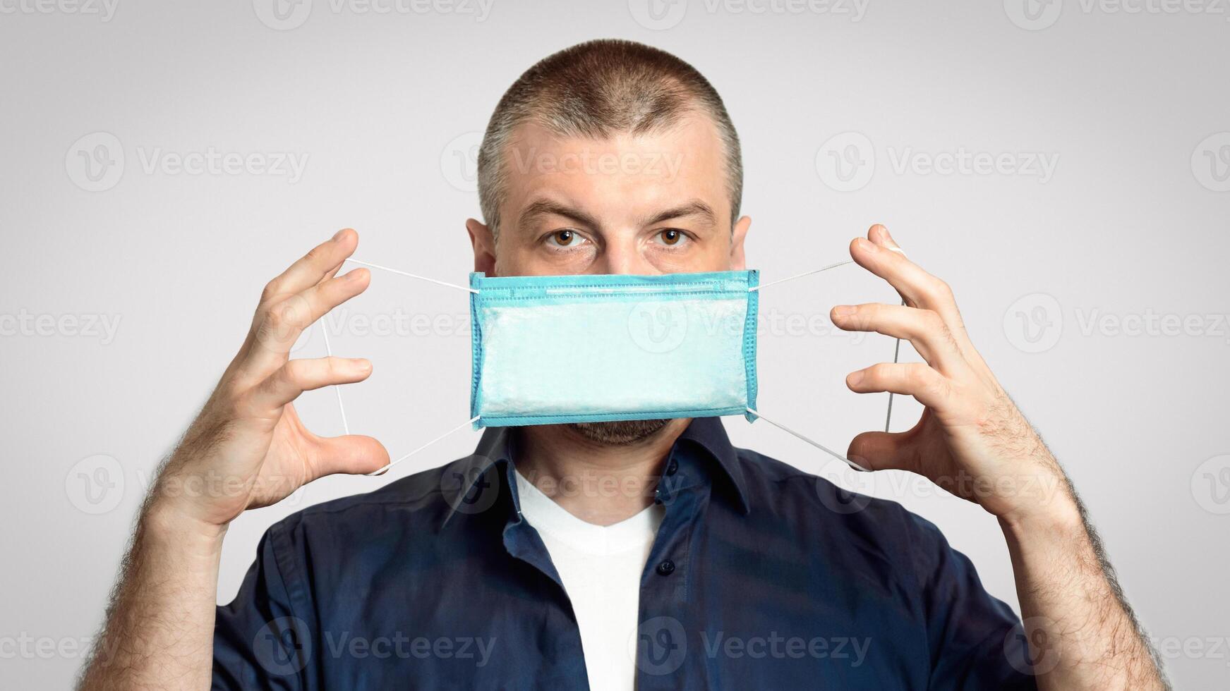 Coronavirus Prevention. Man Showing How To Wear Medical Mask Standing Over Gray Background In Studio. Panorama photo