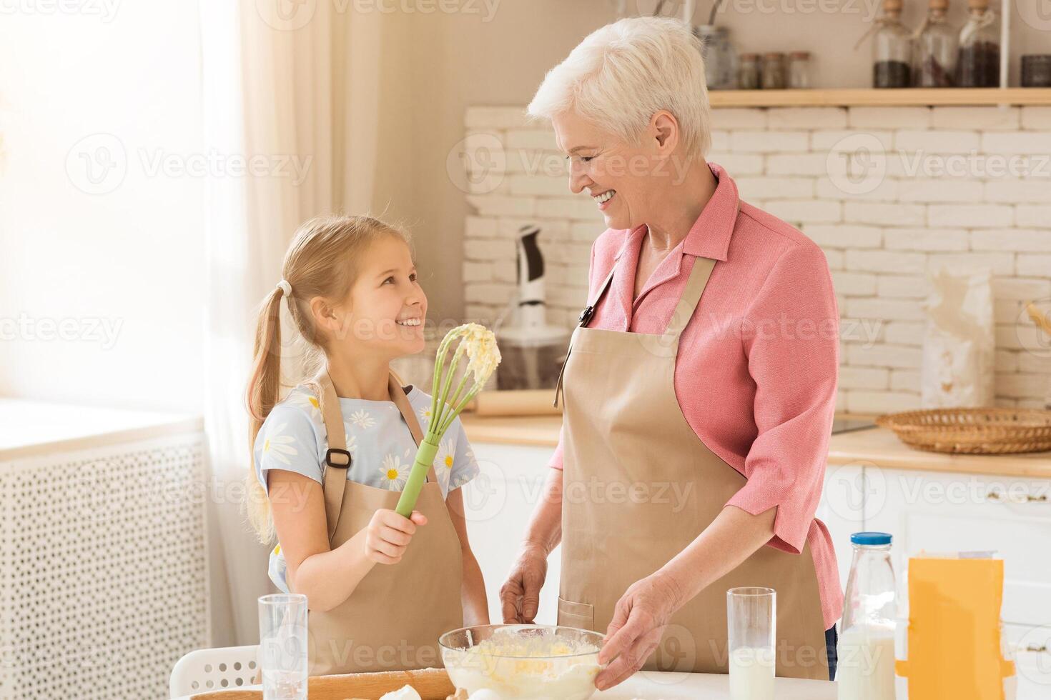 Happy family. Adorable little girl helping her grandma to bake in kitchen, empty space photo