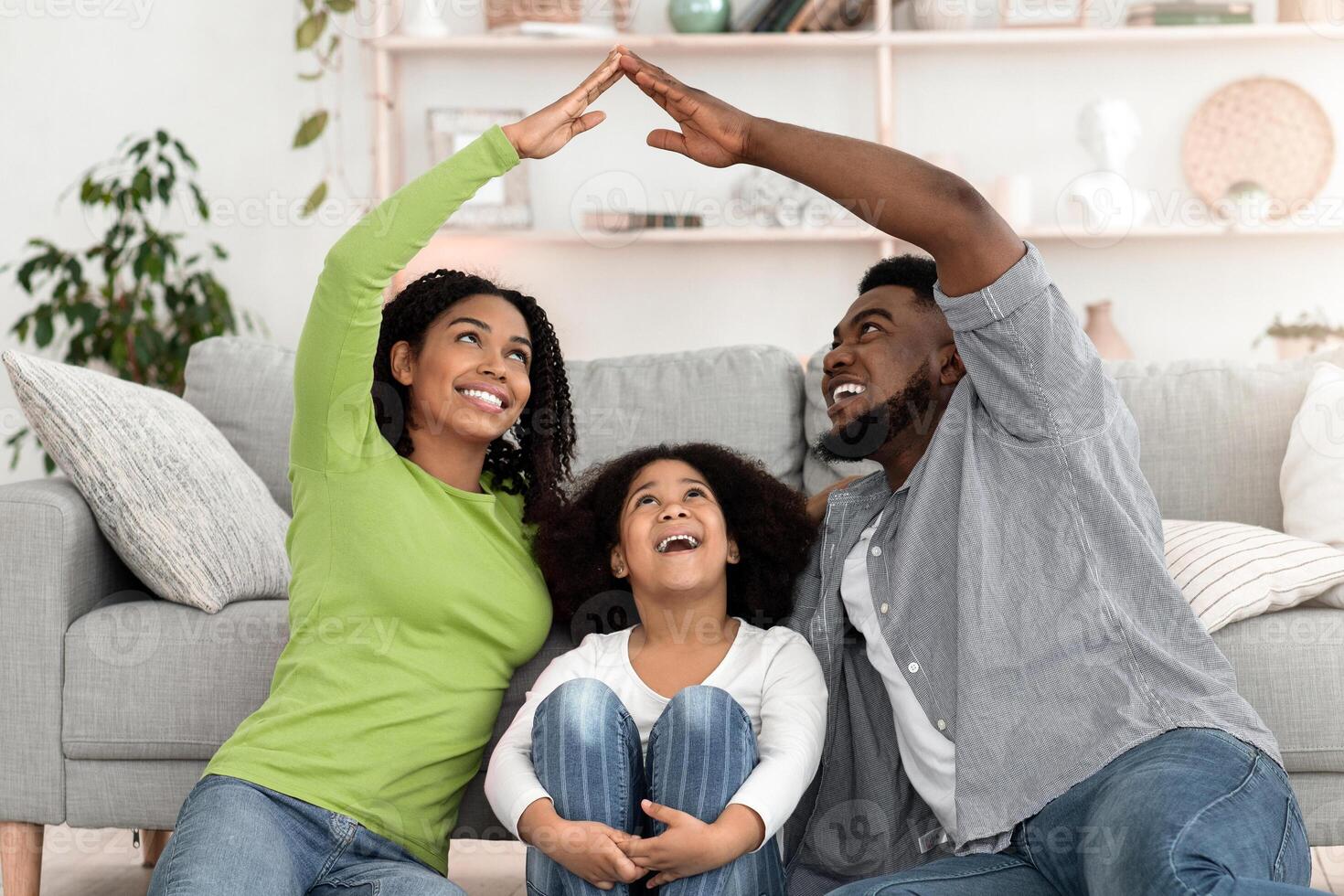 Family Insurance And Housing Concept. Black Father And Mother Joining Hands Making Symbolic Roof Above Head Of Their Little Daughter photo