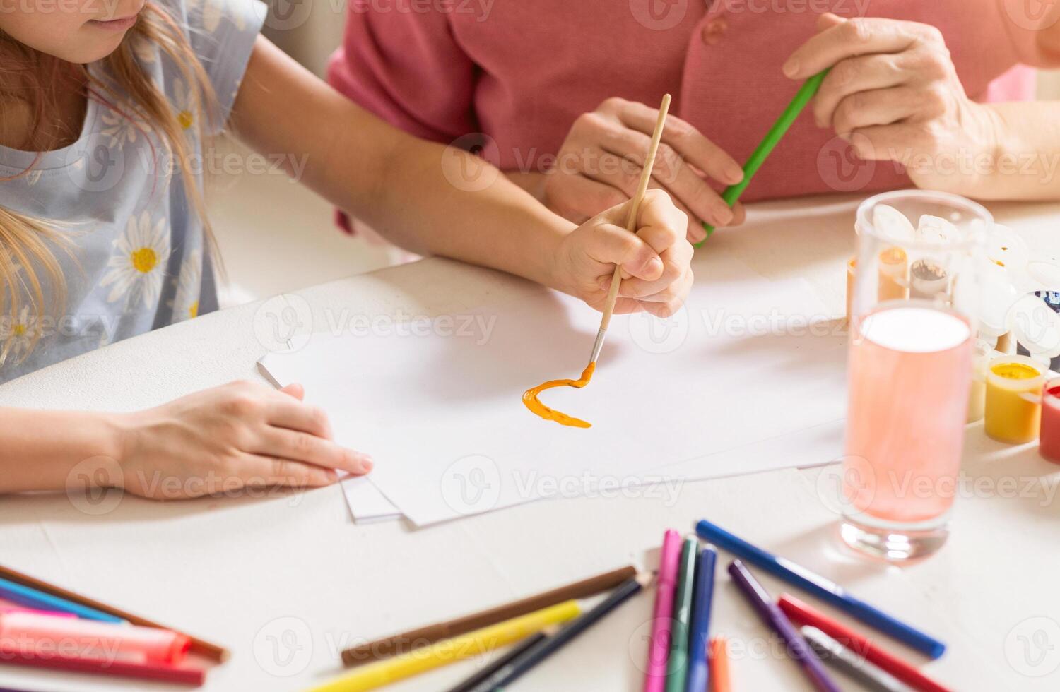 Creative family pastimes. Little girl and her granny painting at table indoors, closeup view photo