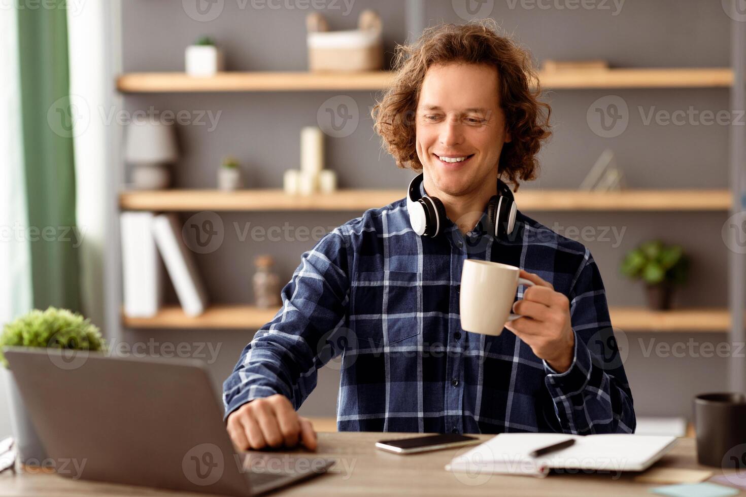 Successful Millennial Businessman At Laptop Drinking Coffee Enjoying Work Sitting At Workplace. Young Empolyee Worker Using Computer In Modern Office. Business People And Entrepreneurship photo