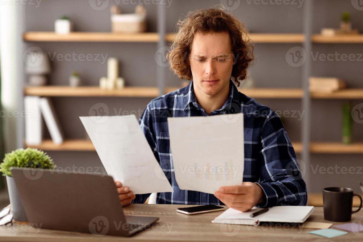 Serious Businessman Reading Business Reports And Financial Bills Looking Through Papers And Documents Sitting At Workplace In Modern Office. Selective Focus photo