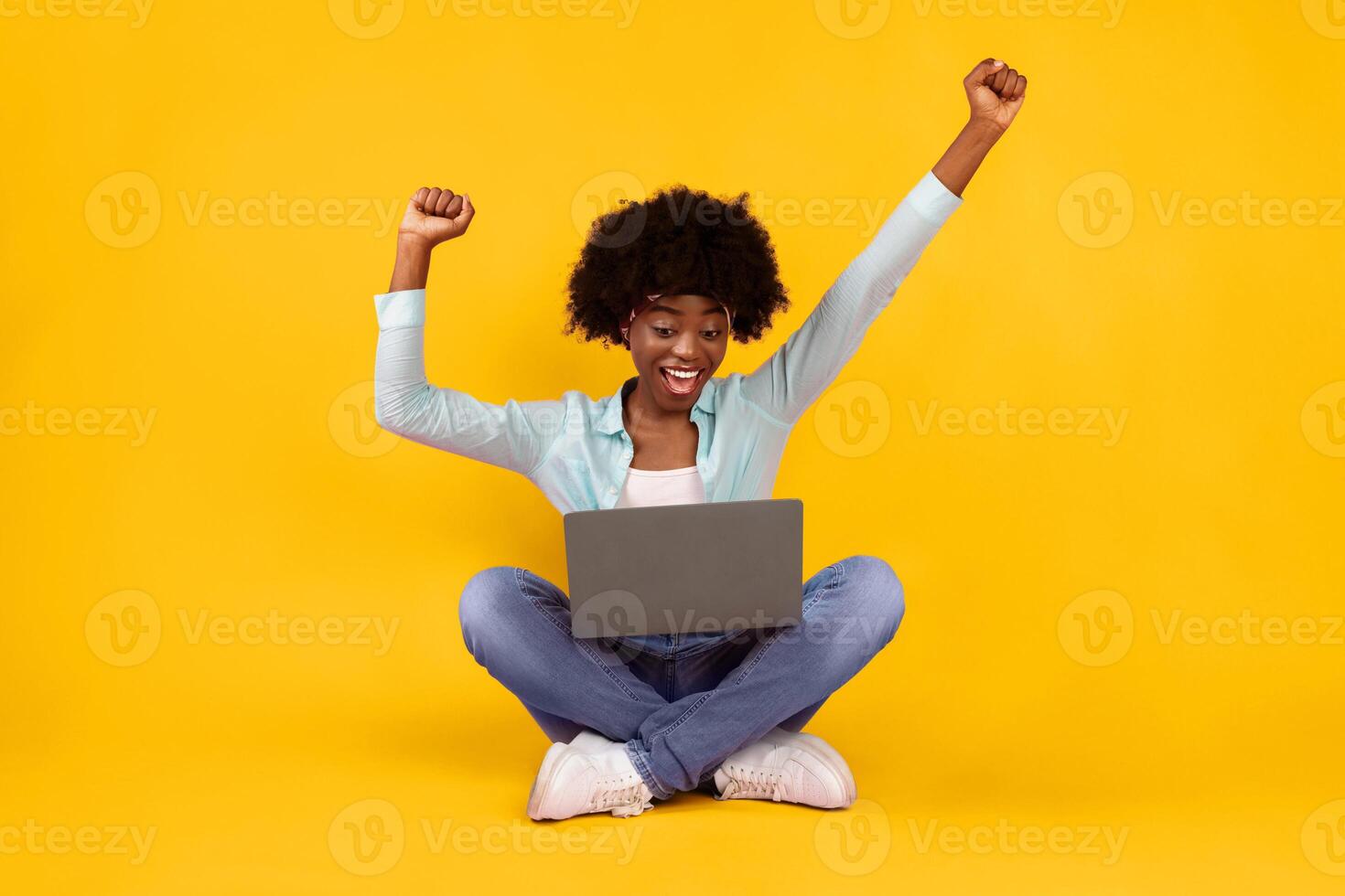Excited African Woman With Laptop Shaking Fists In Joy And Gesturing Yes Celebrating Great News Sitting On Floor In Studio Over Pink Background. Joyful Lady Posing With Computer. Internet And Gadgets Concept photo
