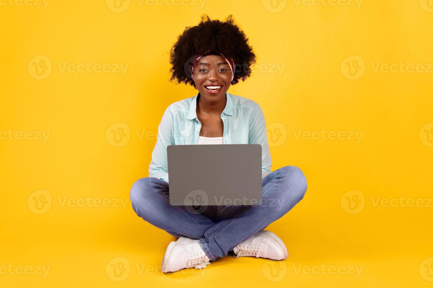 Happy African American Woman Using Laptop Smiling To Camera Sitting On Floor Posing Over Pink Background. Black Female Browsing Internet And Networking. E-Learning, Distant Work Online And Freelance photo