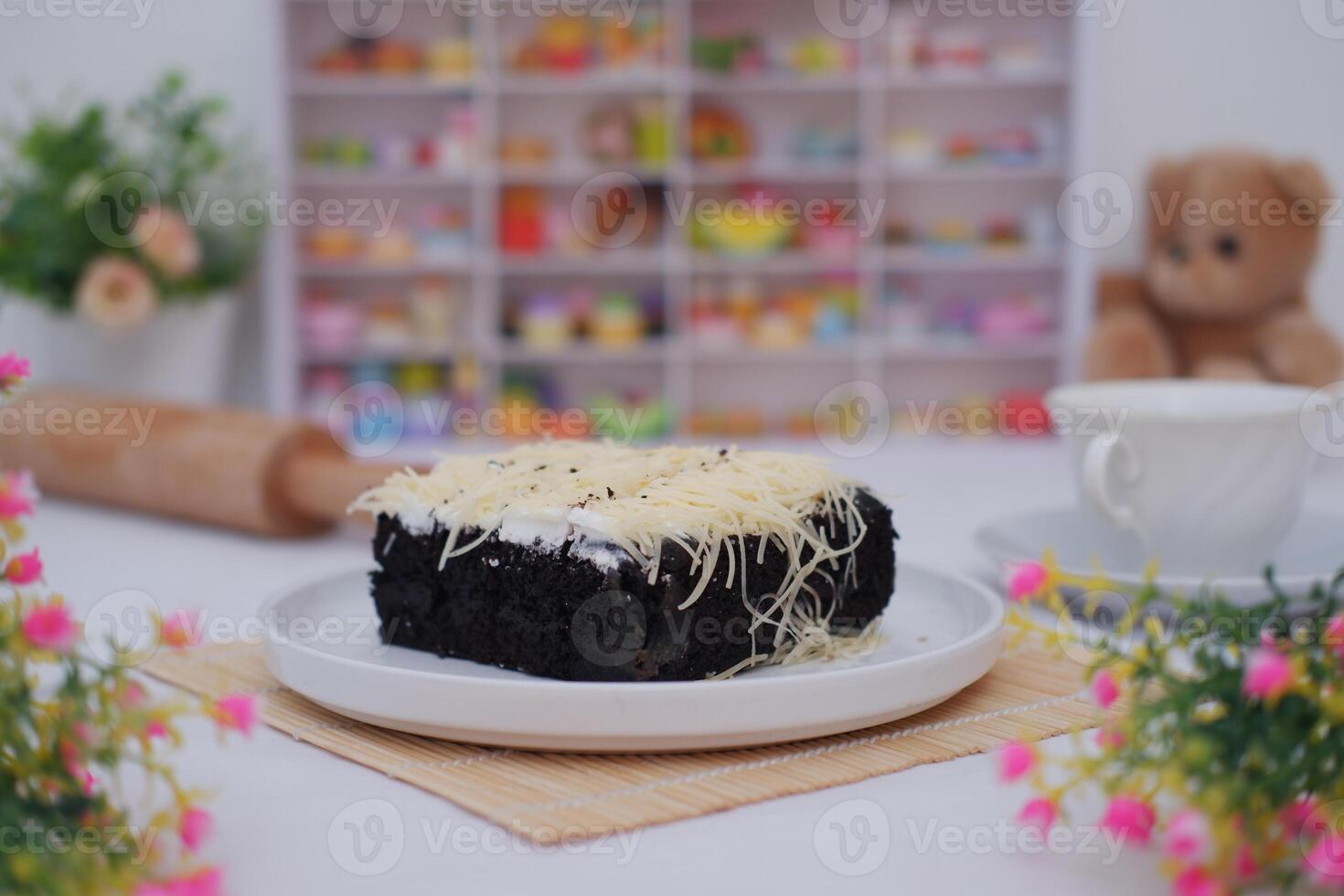 A piece of black cake topped with shredded cheese photo