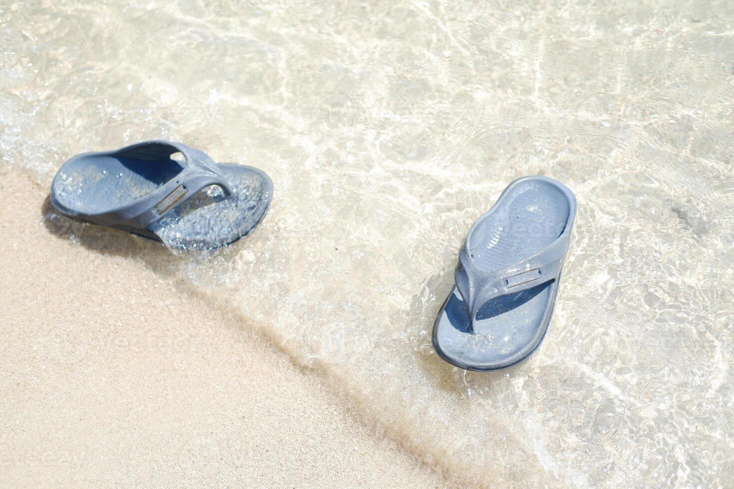 flip flops on the sand at the beach with sea background photo