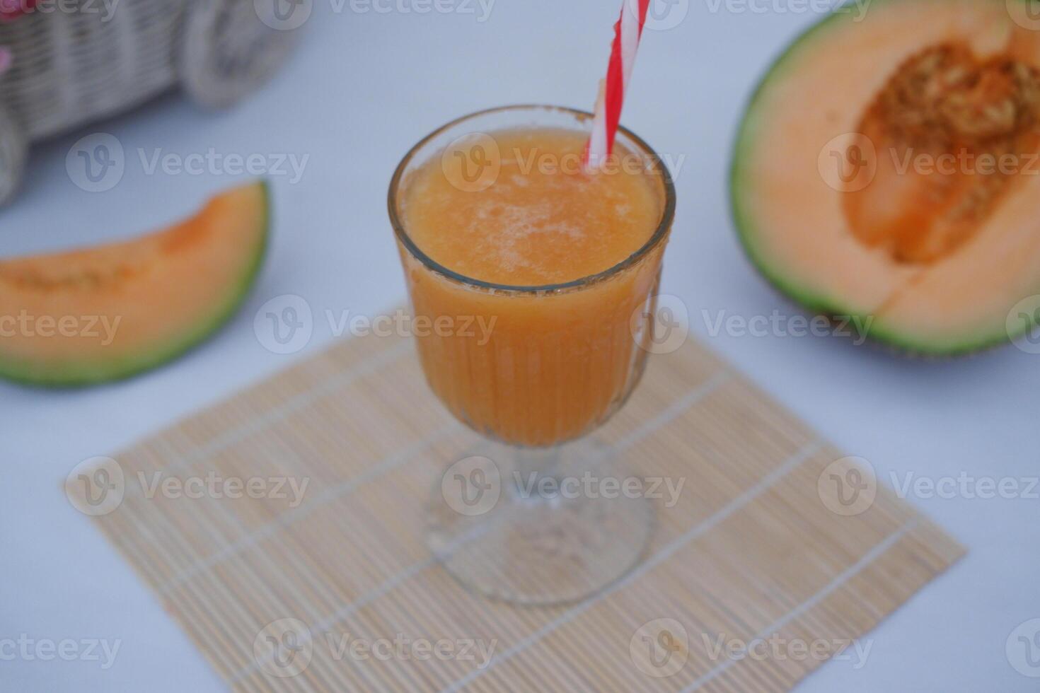 Melon juice in a glass and fresh melon on the table photo