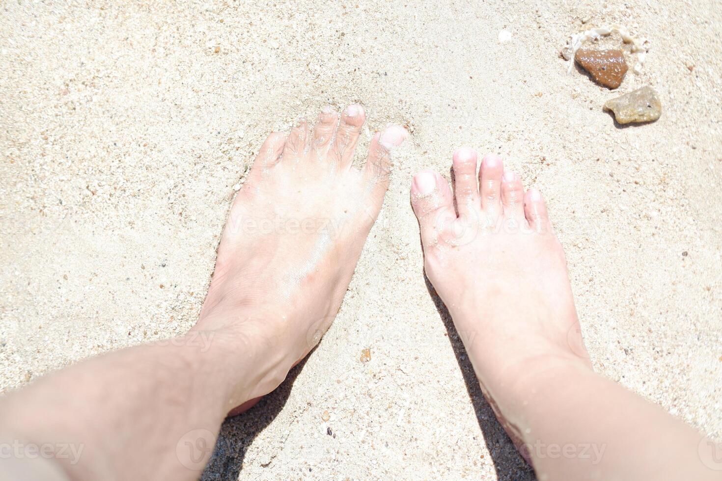 Woman's and men's feet on the sand at the beach in the summer. photo